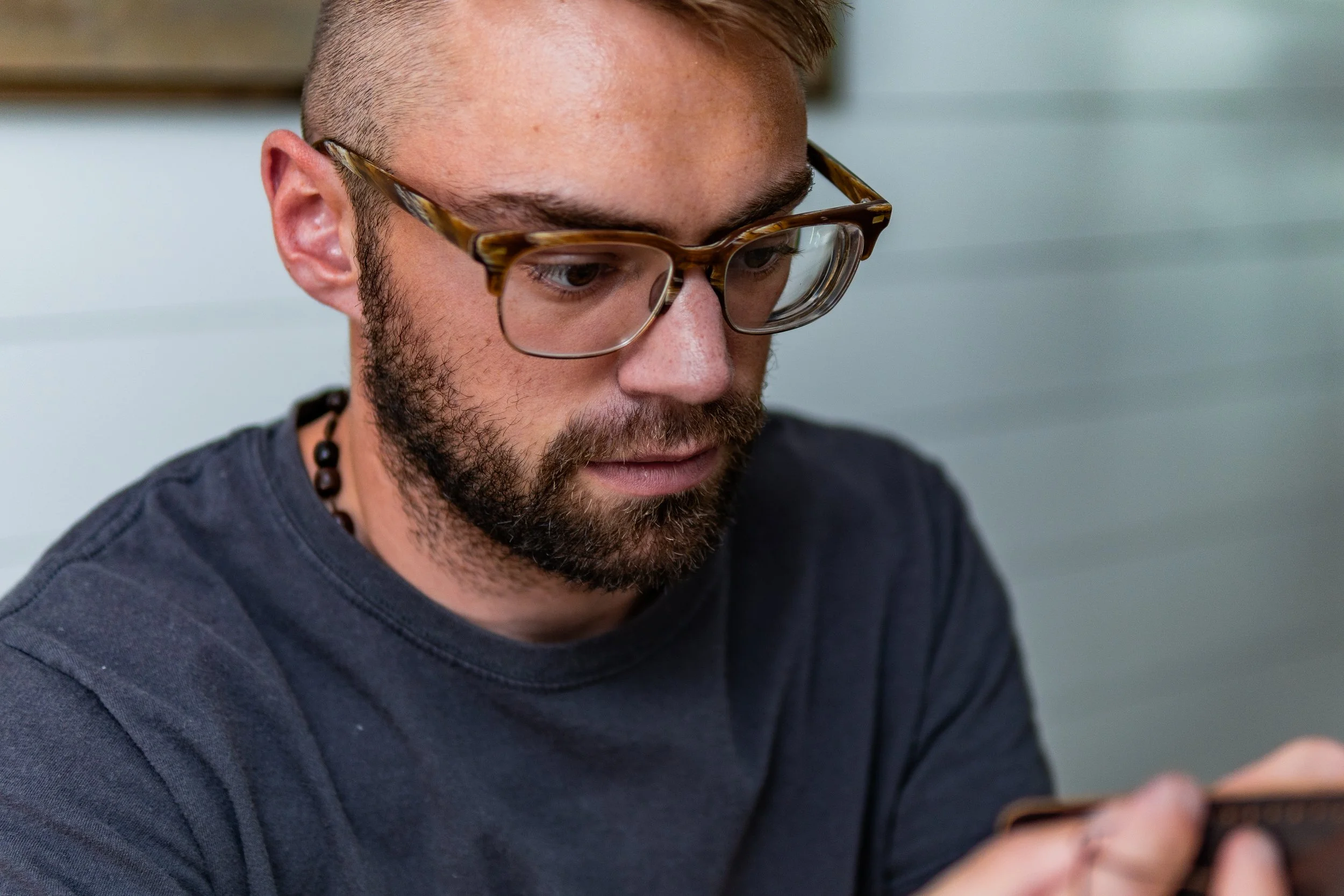 A man with glasses and a beard looking at his phone.