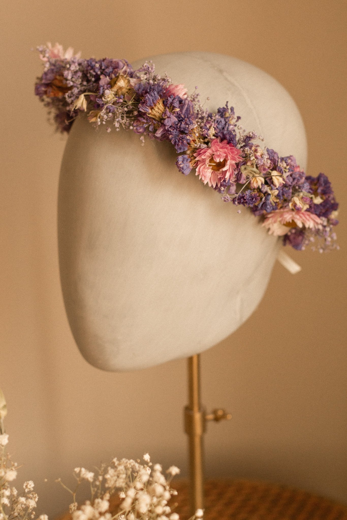 Ein weißer Hut mit einem Kranz aus getrockneten rosa und lila Blumen.