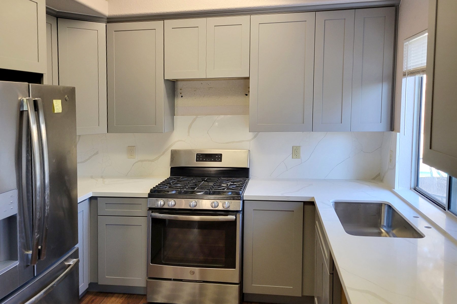 Kitchen: Light Grey cabinet finish, shaker style. Other finishes: Calacatta Gold countertop, stainless steel appliances, and  stainless steel single-bowl sink. 