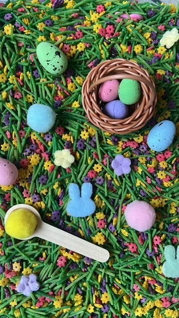 green dried rice, with yellow, pink and puple died flower pasta for a sensory bin. mini speckled eggs and scoop
