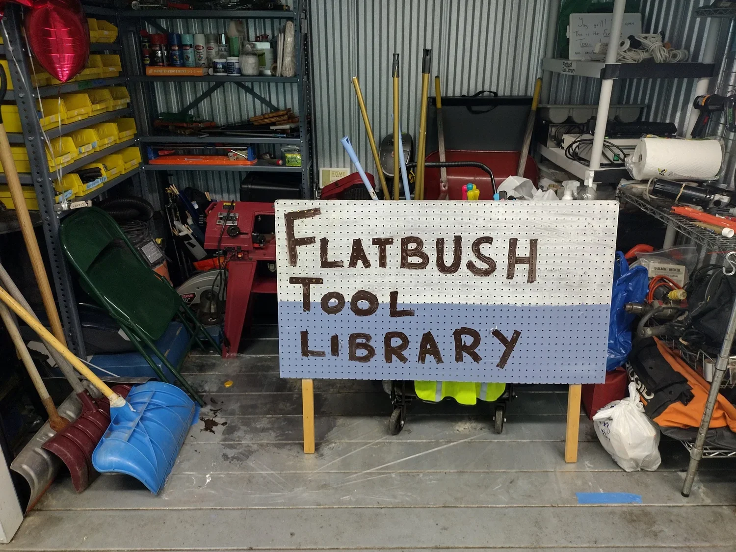 Tools jumbled in a dark storage shed with a sign reading: Flatbush tool Storage Shed
