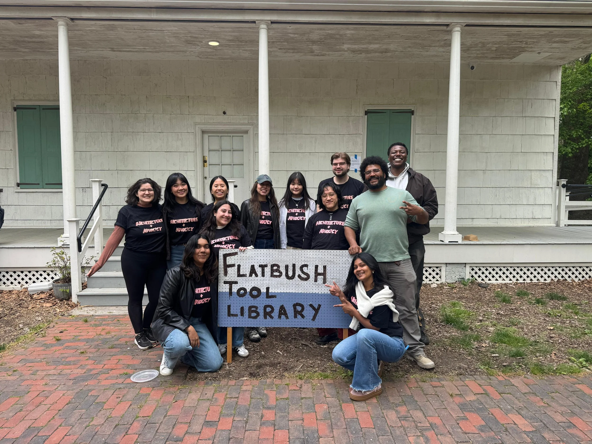 A group of ~10 young people gathered around the Flatbush Tool Library Sign