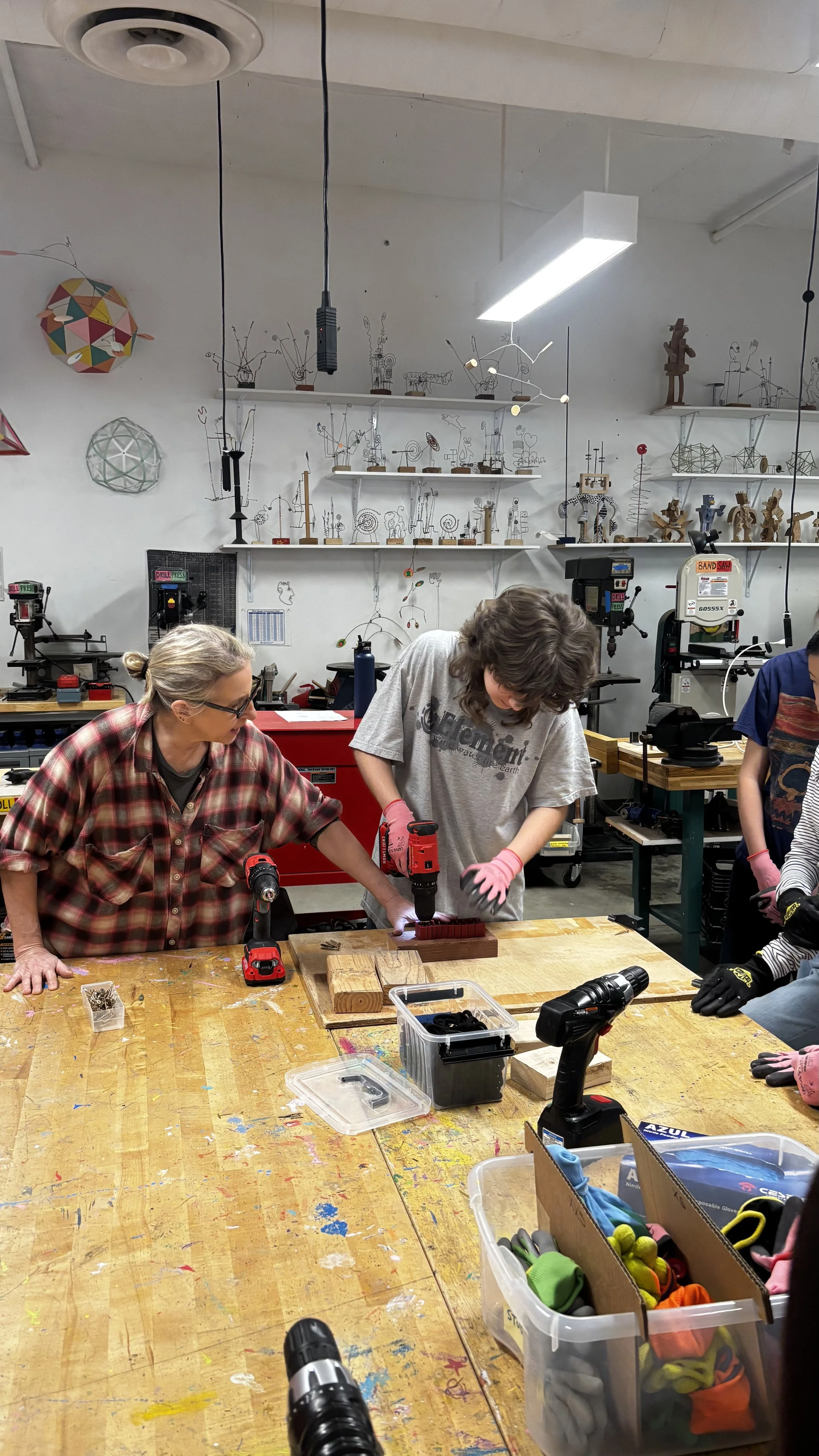 Student drills into test wood while teacher looks on