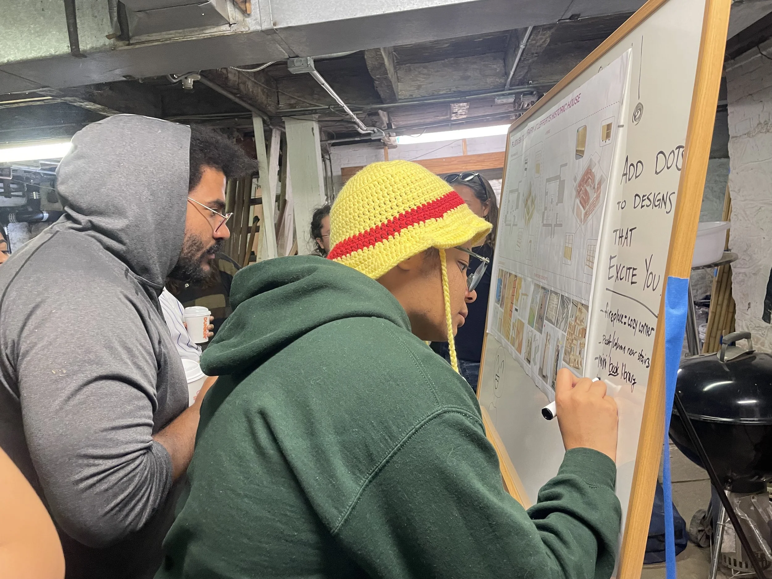 Man writes on a dry-erase board  while another man looks on
