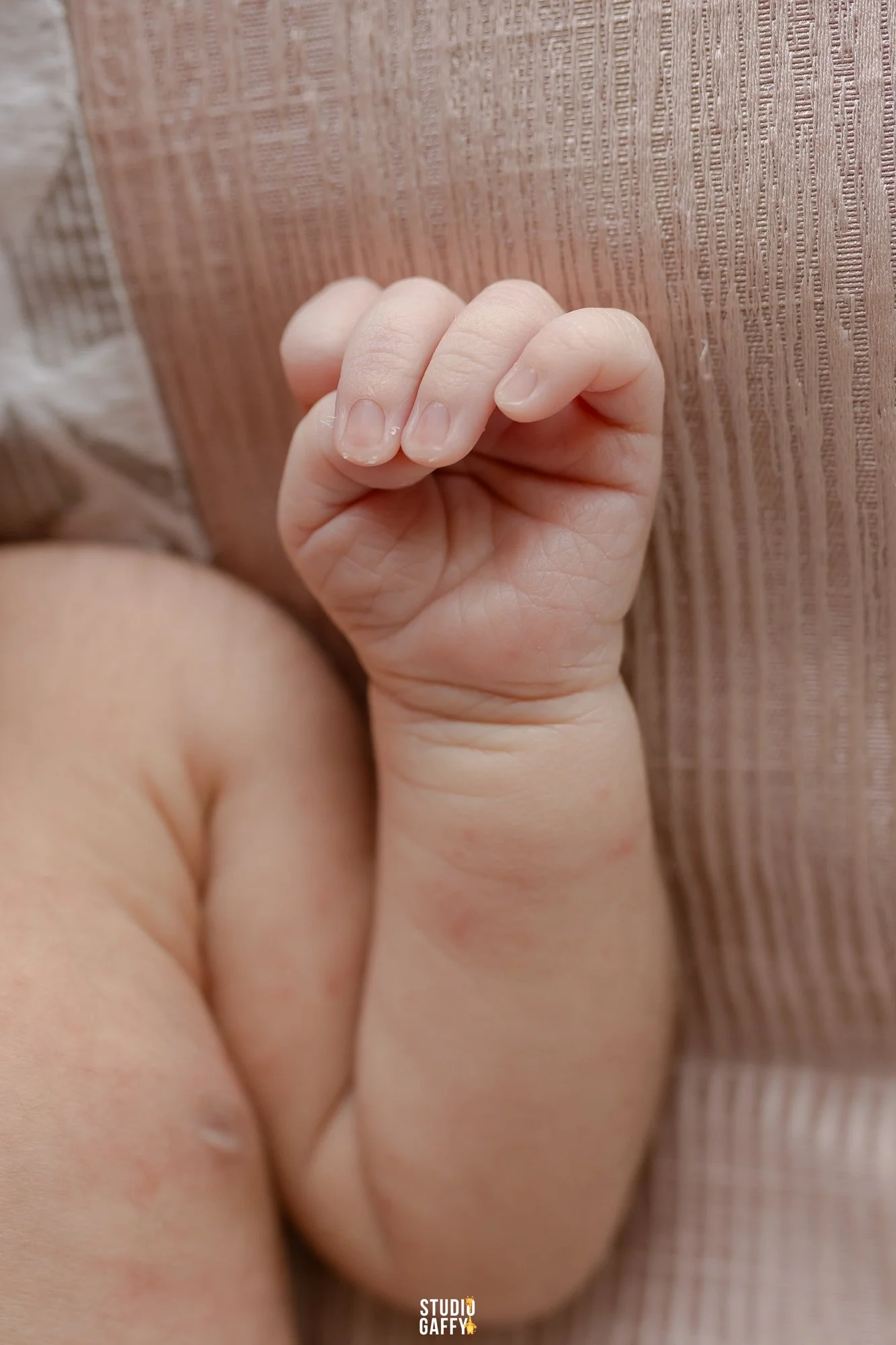 Close-up of a baby's hand resting on a textured fabric surface.