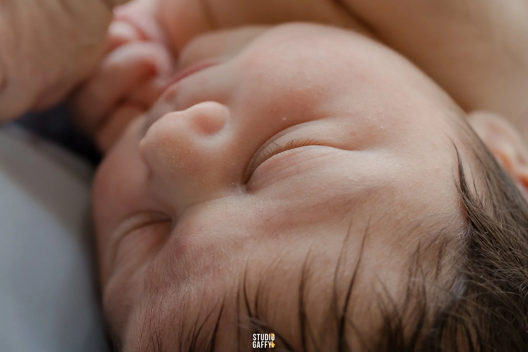 Close-up of a person lying down with a hand gently touching their face, focusing on skin and facial features.