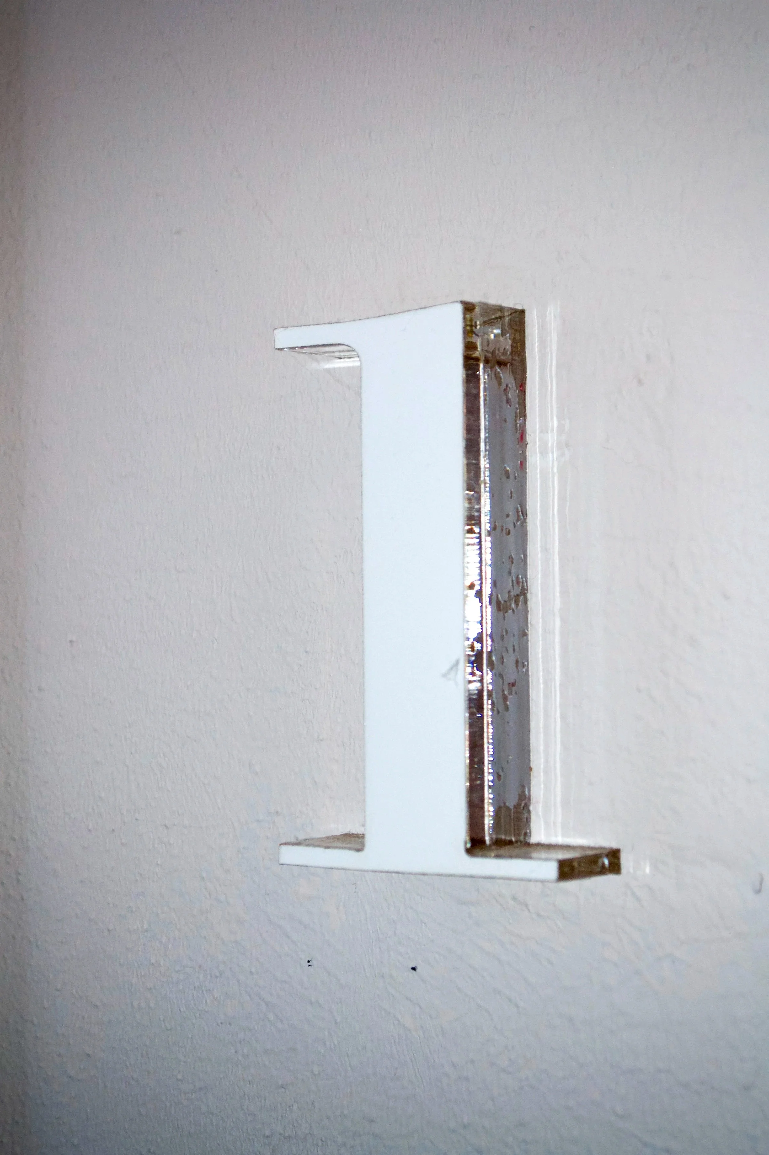 Close-up of a white number 1 sign mounted on a wall.