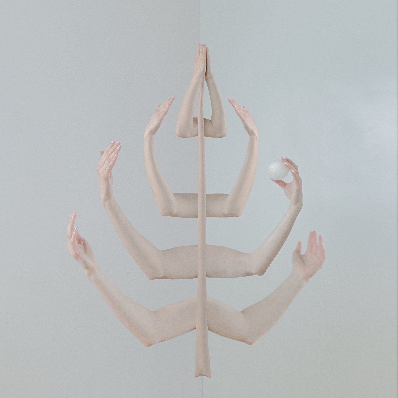 Gray background within four light skin arms mirroring in the air another four light skin arms from left to right and only an arm holding a white ball.