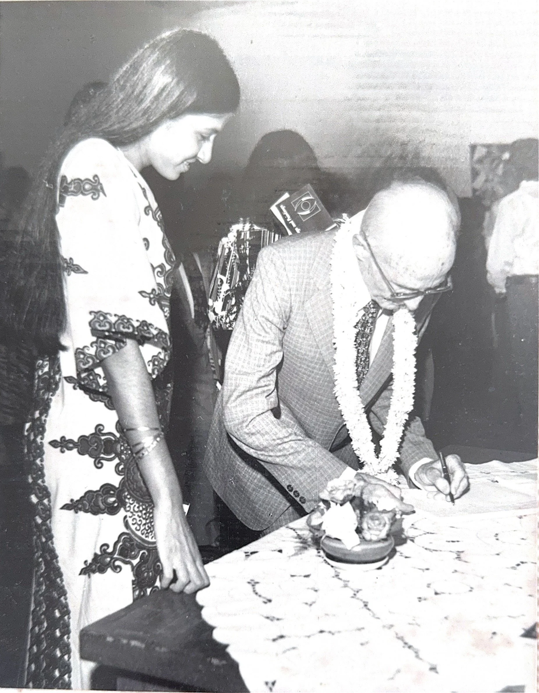 The artist with the French Cultural Ambassador at her first solo exhibition over 46 years ago. The ambassador signs the guest book as the artist looks on, marking the beginning of her artistic journey.