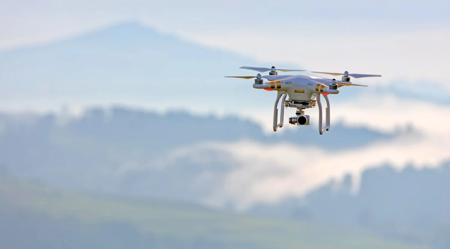 Survey drone in flight above open countryside
