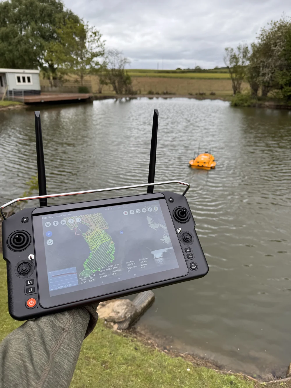Surveyor operating the autonomous survey vessel from the bank with a handheld controller