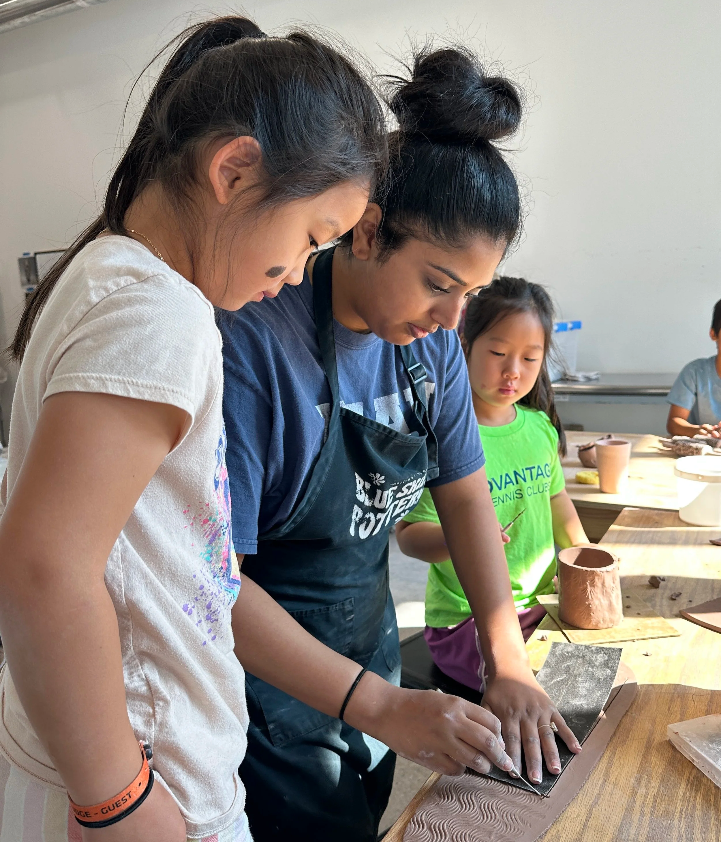 Two children work on their projects with an instructor at Blue Skies Pottery in Long Branch, NJ.