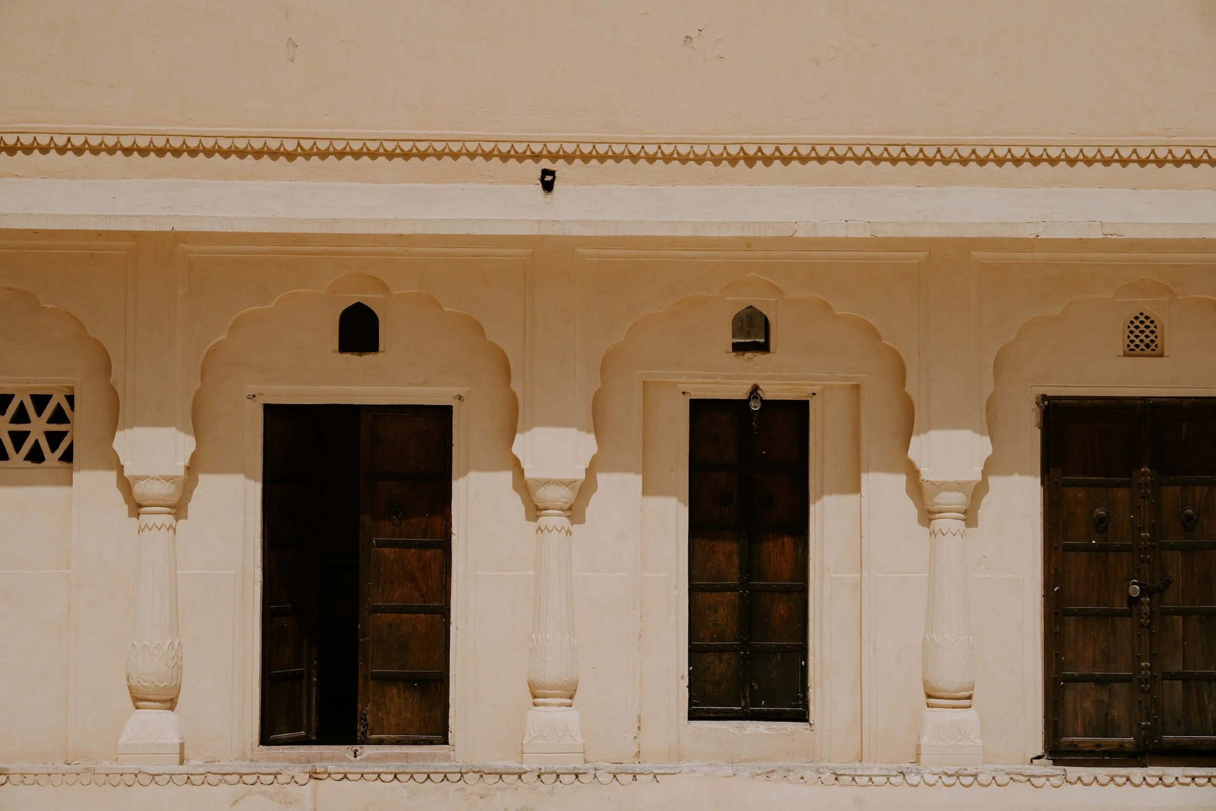 Facade of a traditional Indian building with arches and dark wooden windows.