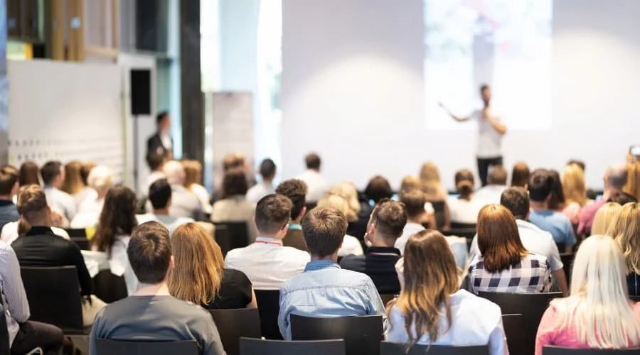 An example of an event audit showing a large group of people seated and listening to a speaker in a conference room.