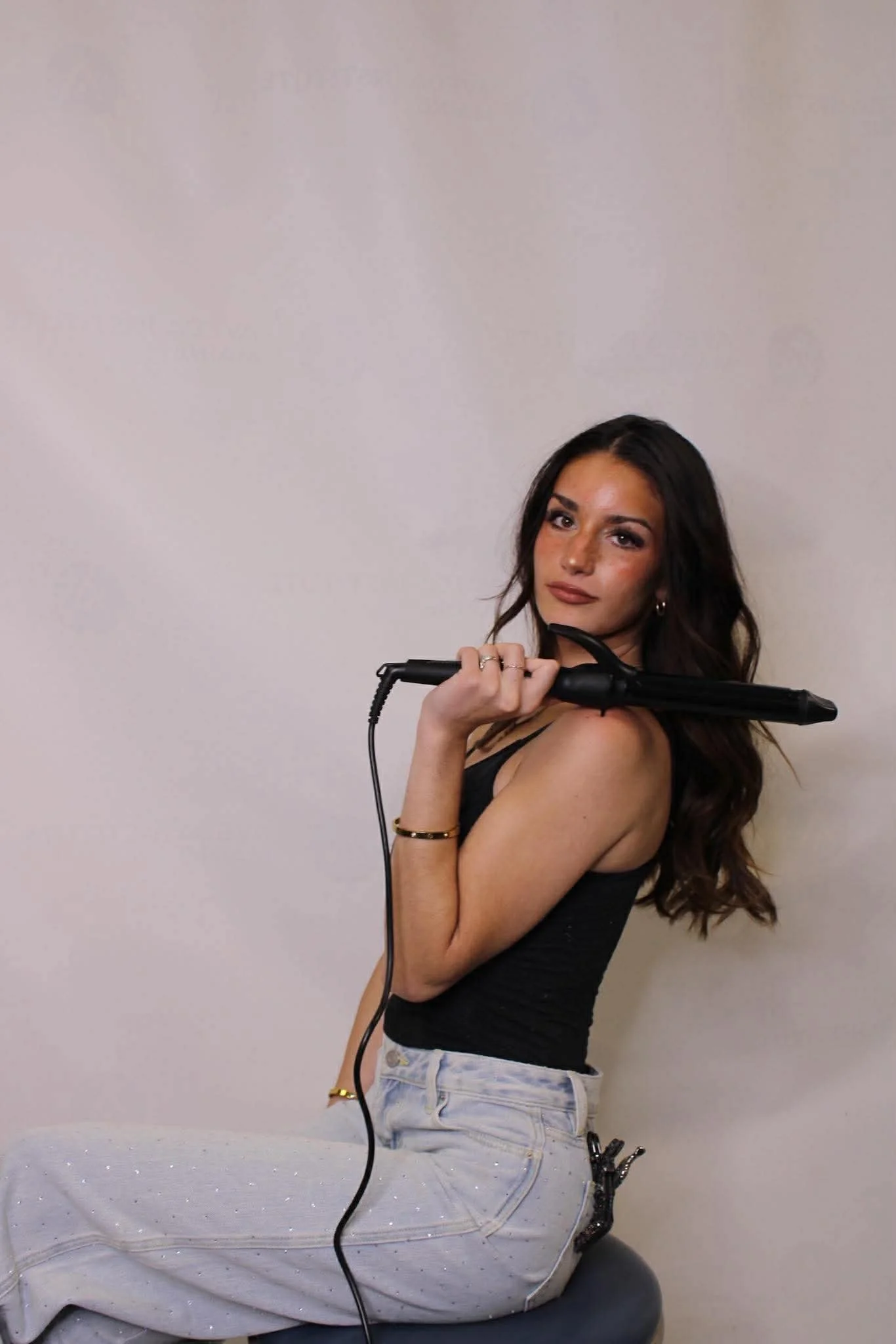 brunette hair dresser holding curling iron