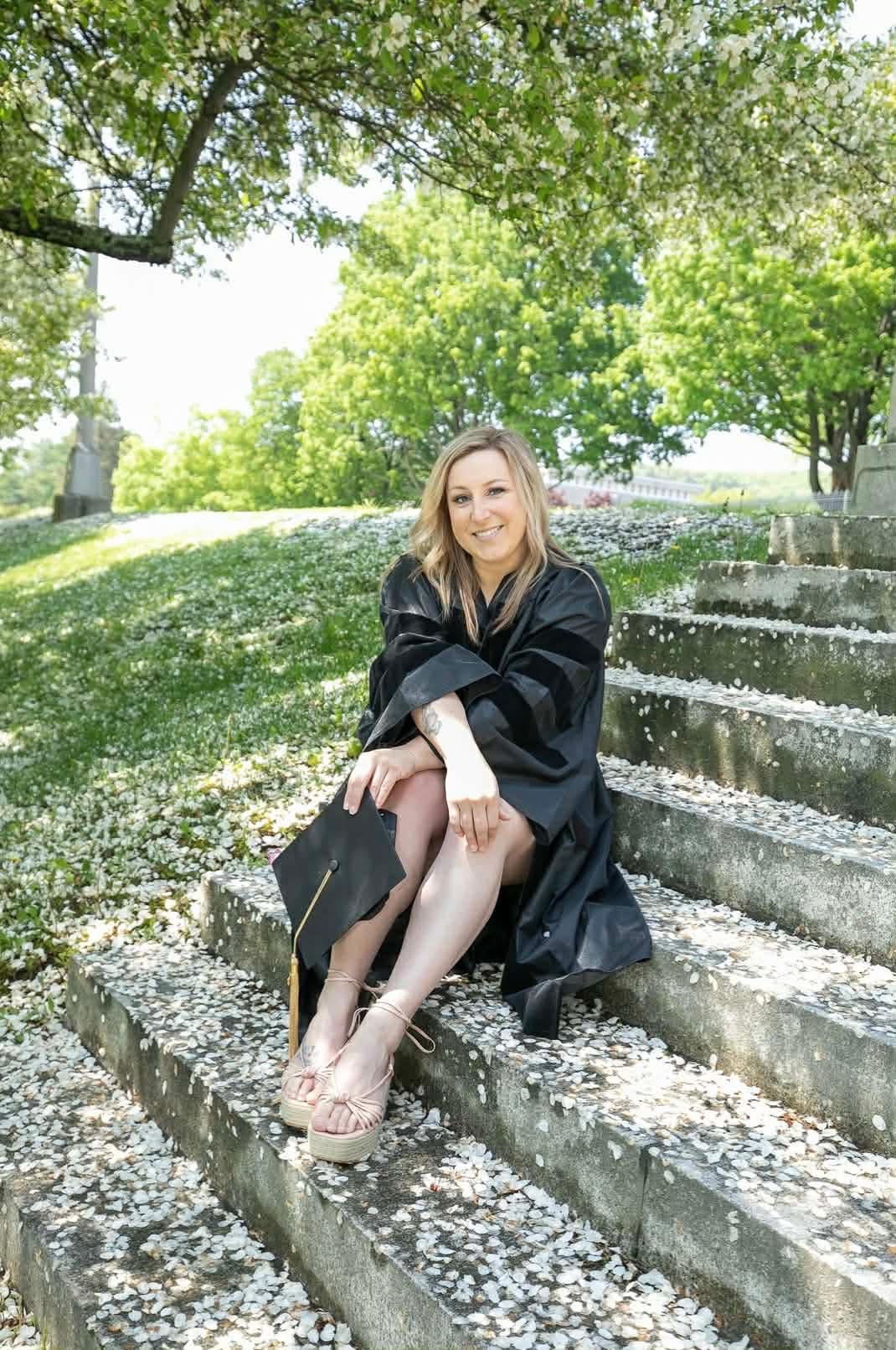 amber nail tech smiling with graduation gown with spring flowers