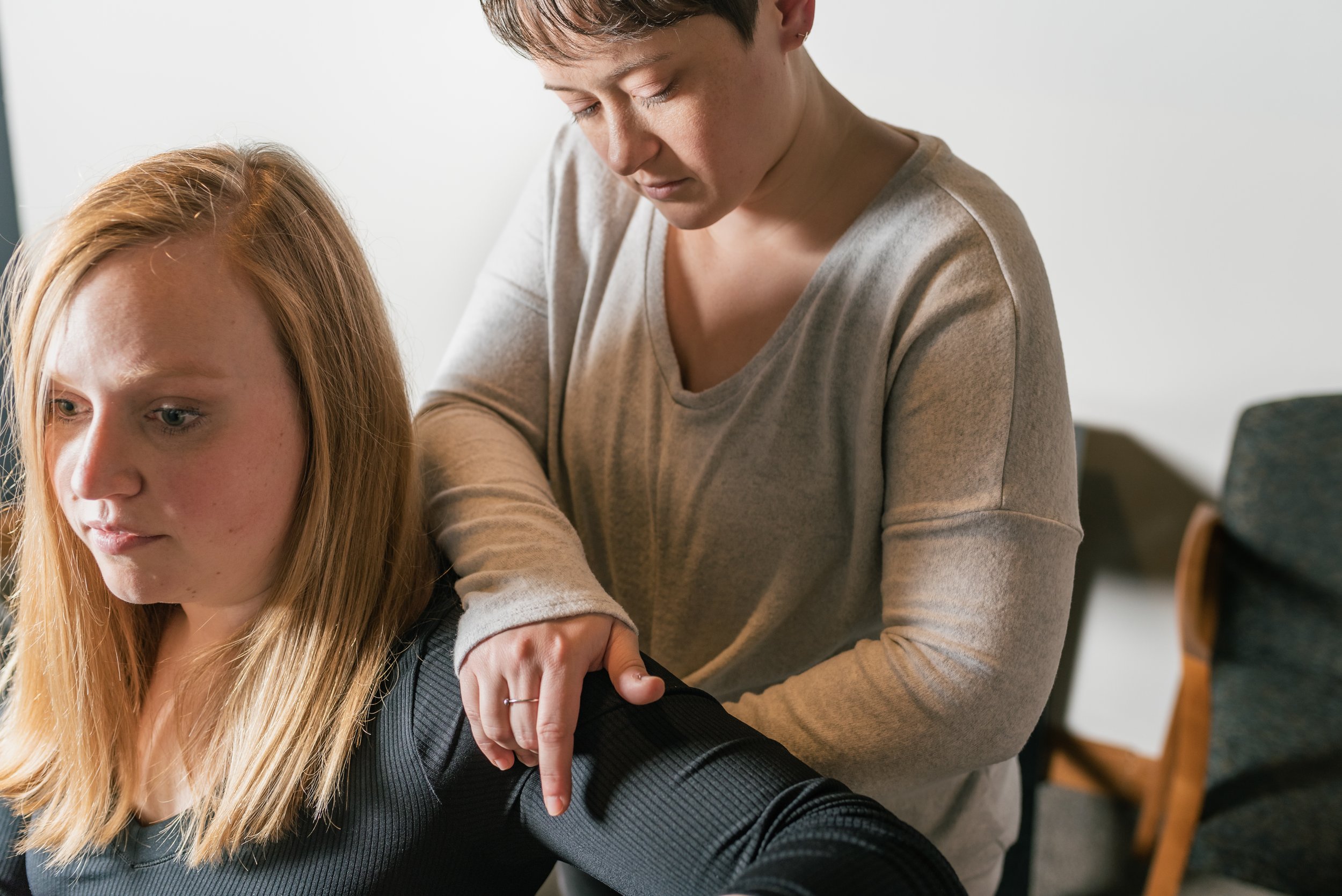 Woman using pressure point to back while also touching arm of patient