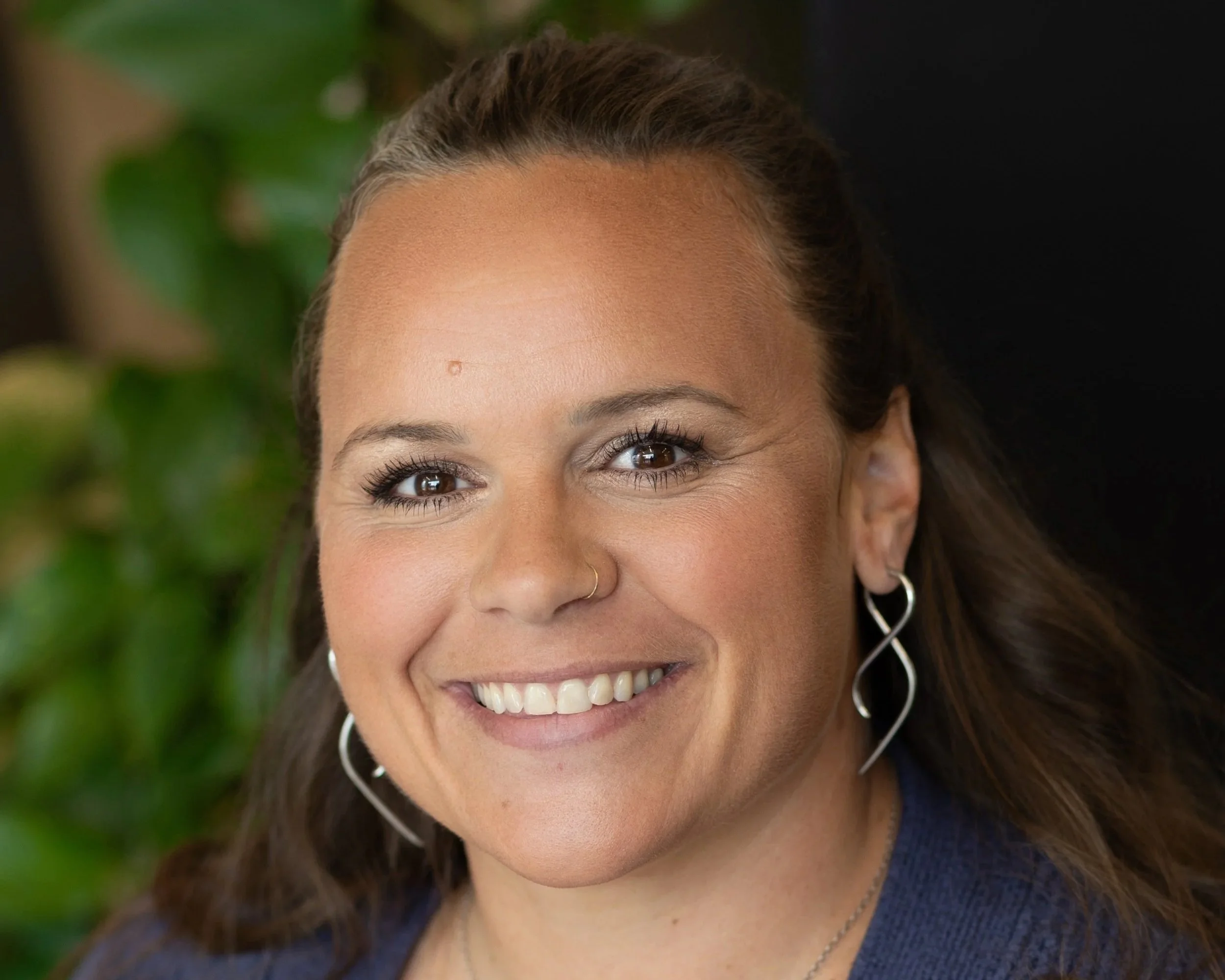 Woman with long brown hair, blue sweater and smiling