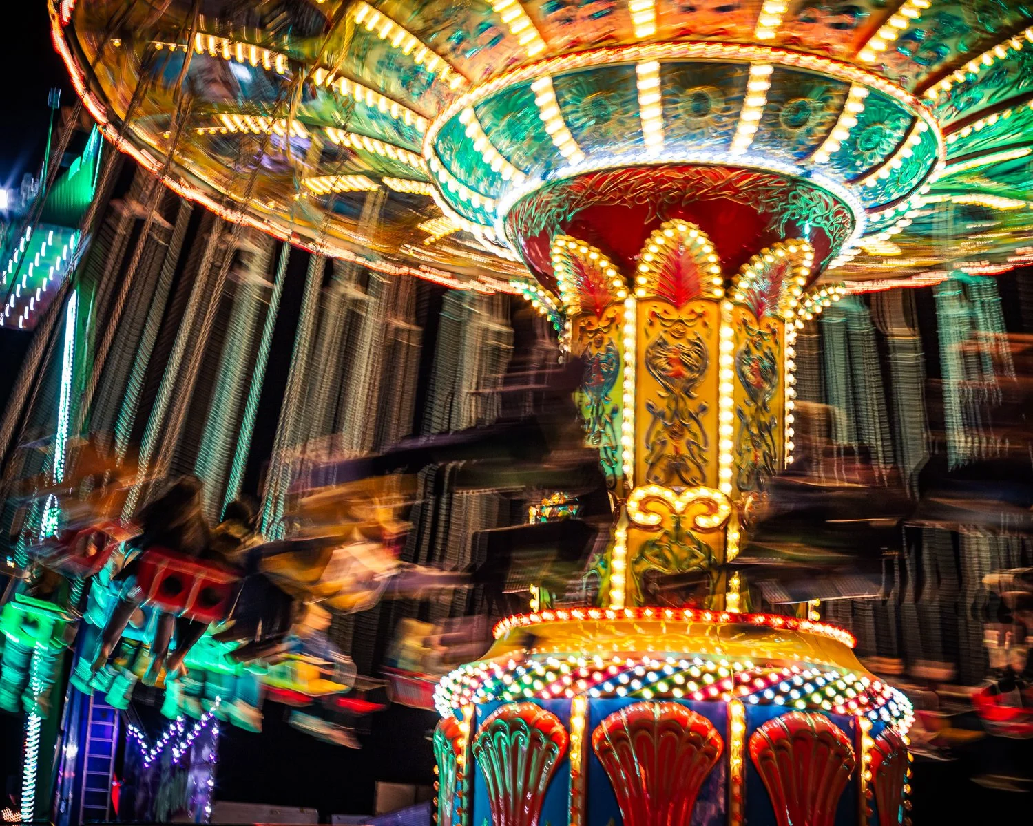 Colorful carnival ride with bright lights and spinning motion at night.