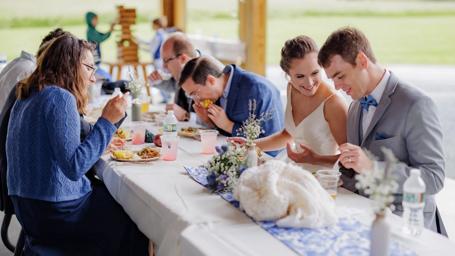 People sitting at a decorated table enjoying a meal at an outdoor wedding reception.