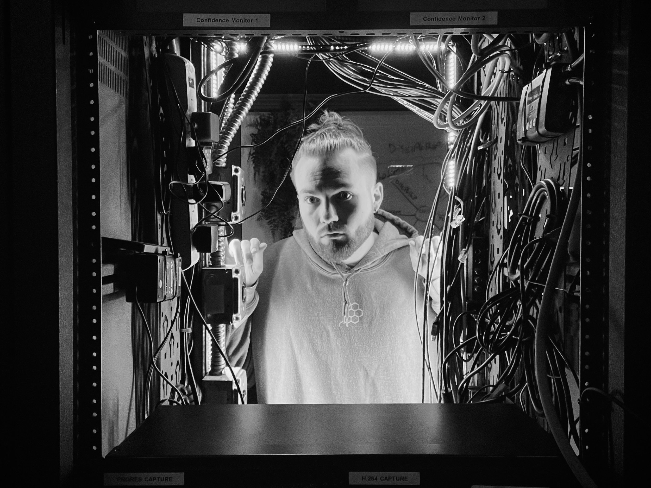 Tristan Mailloux looks into a server rack filled with numerous wires, cables, and electronic equipment in a data center.