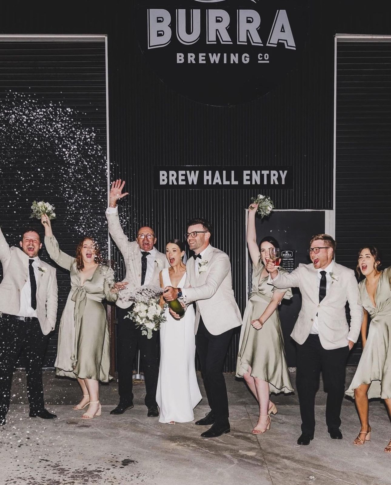 Wedding celebration at Burra Brewing Co, with people throwing confetti and holding bouquets outside the brew hall.