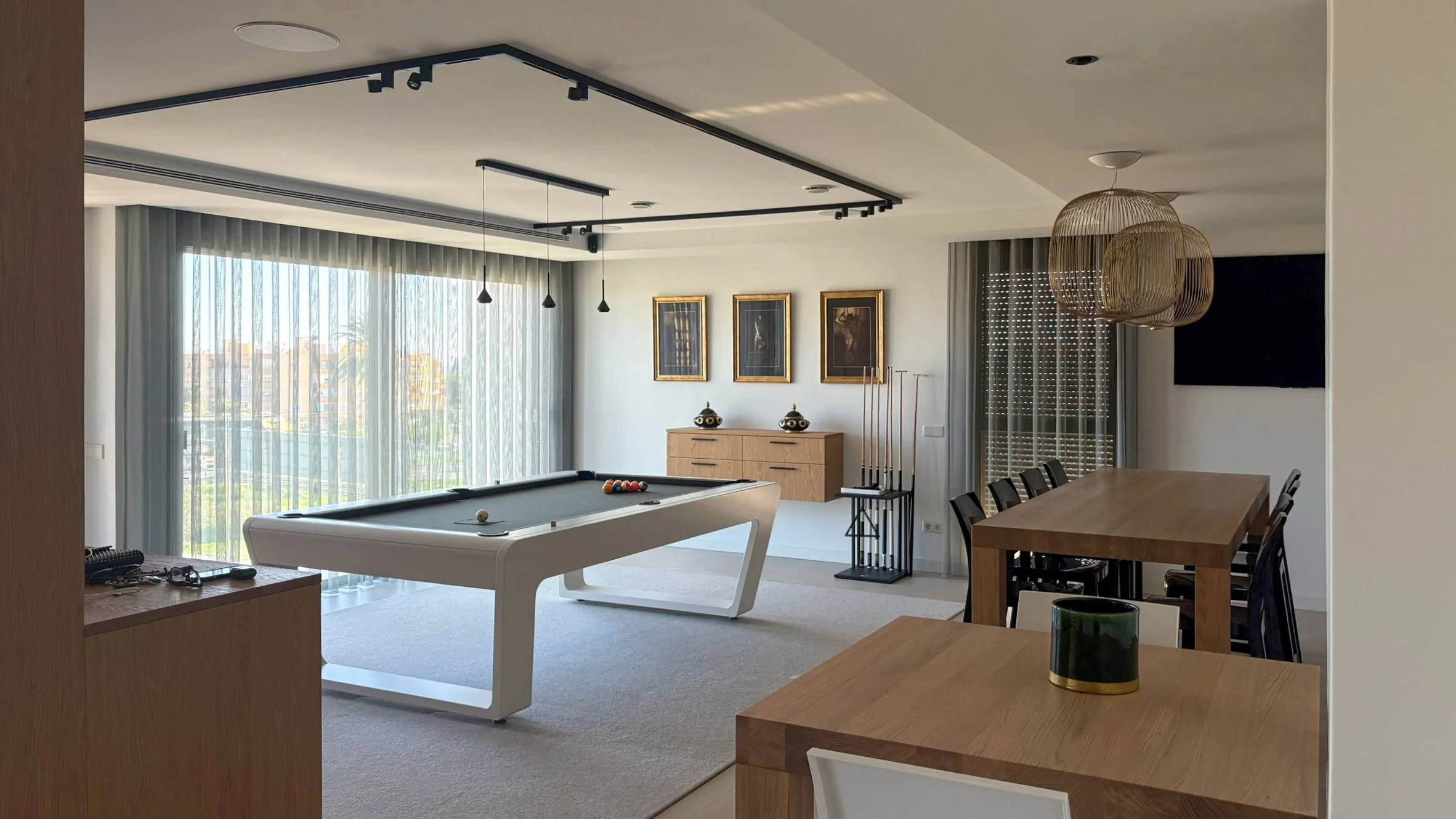 Modern living room with large windows, a pool table, dining area, and minimalist decor.