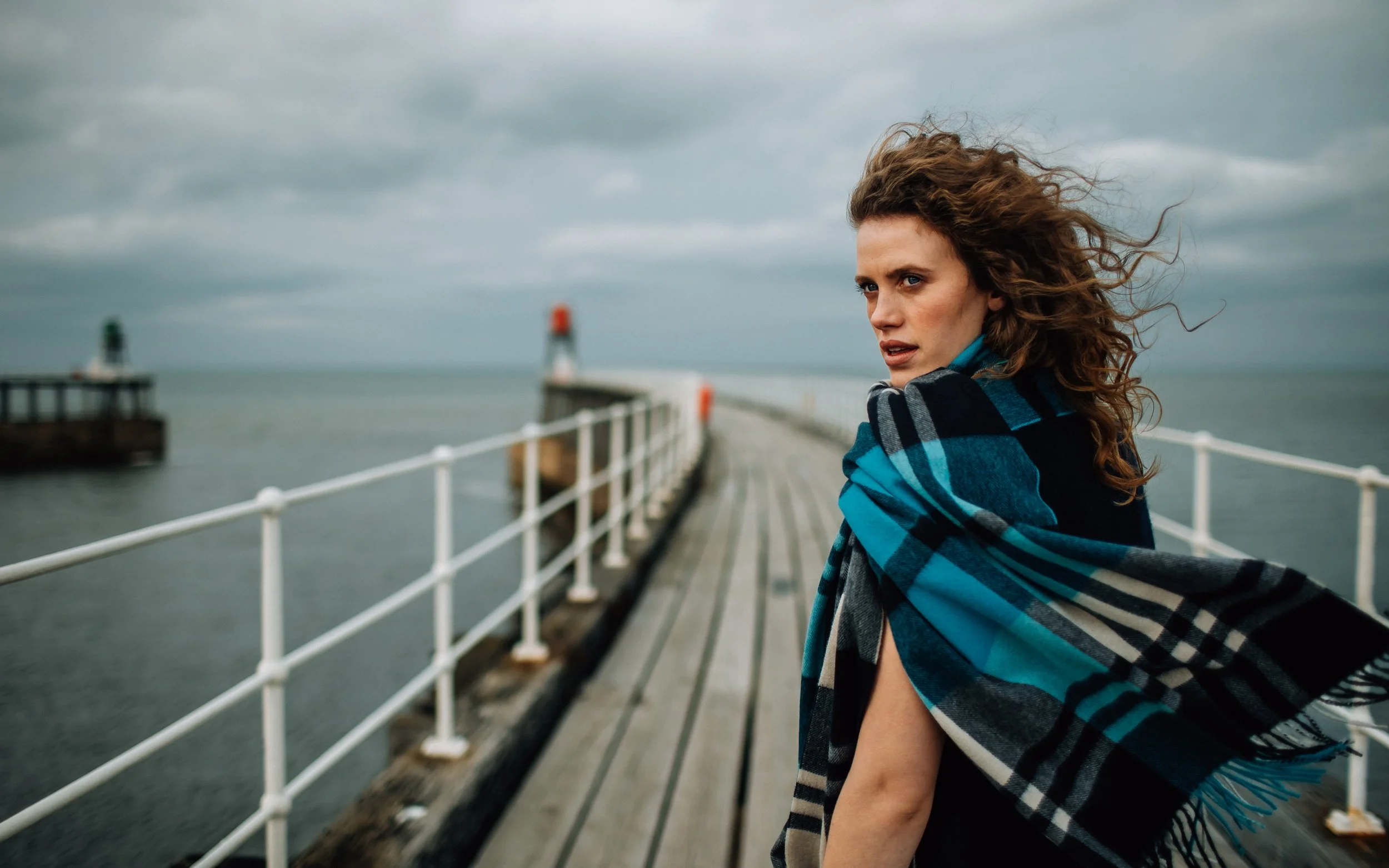 Girl stands on pier in scarf