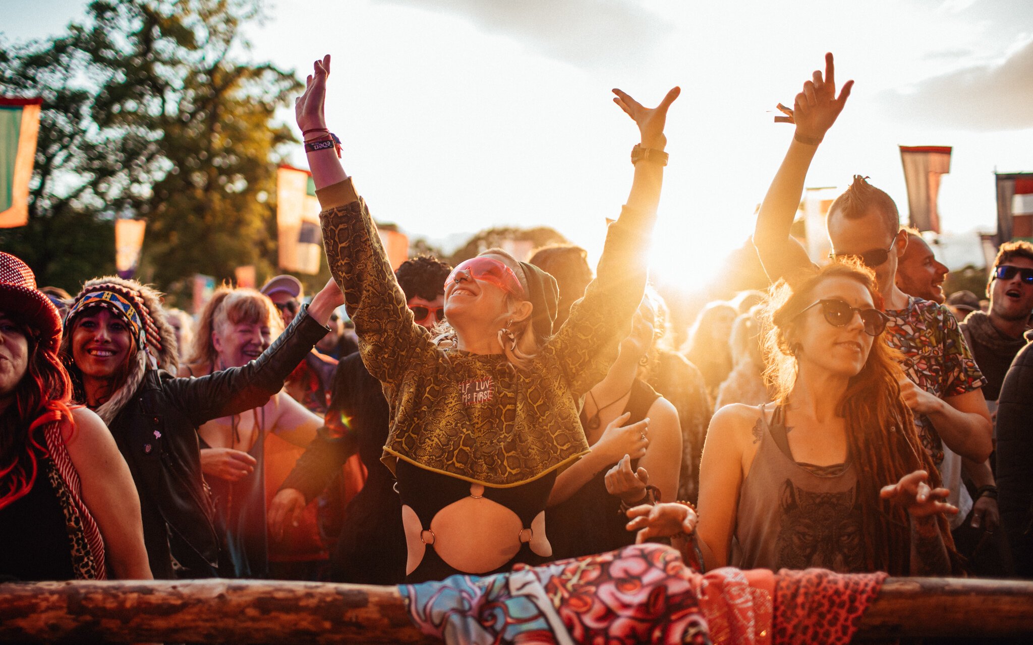  girls in festival outfits dance at a music festival in the sunset