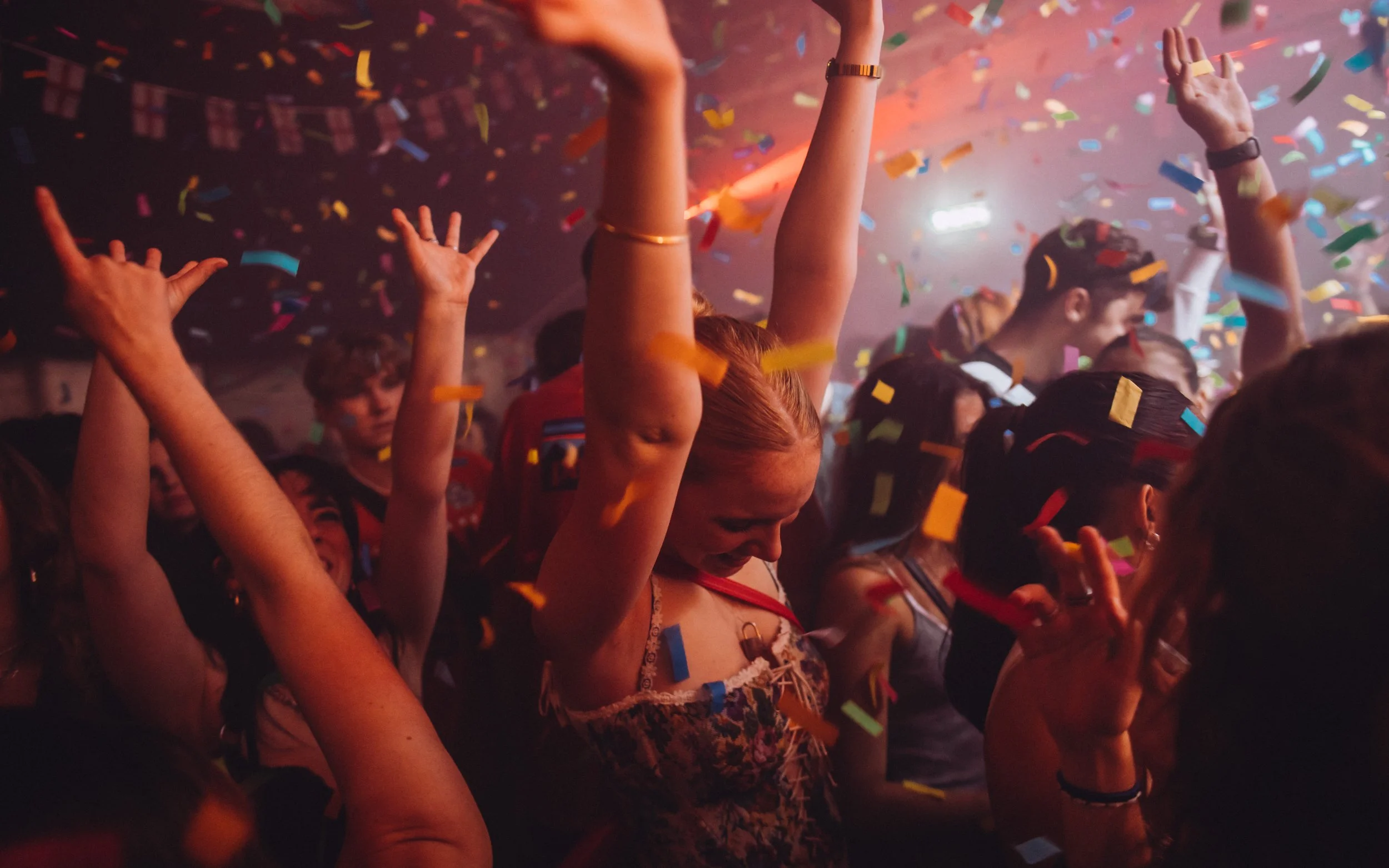  girl, dances, with hands in the air in confetti