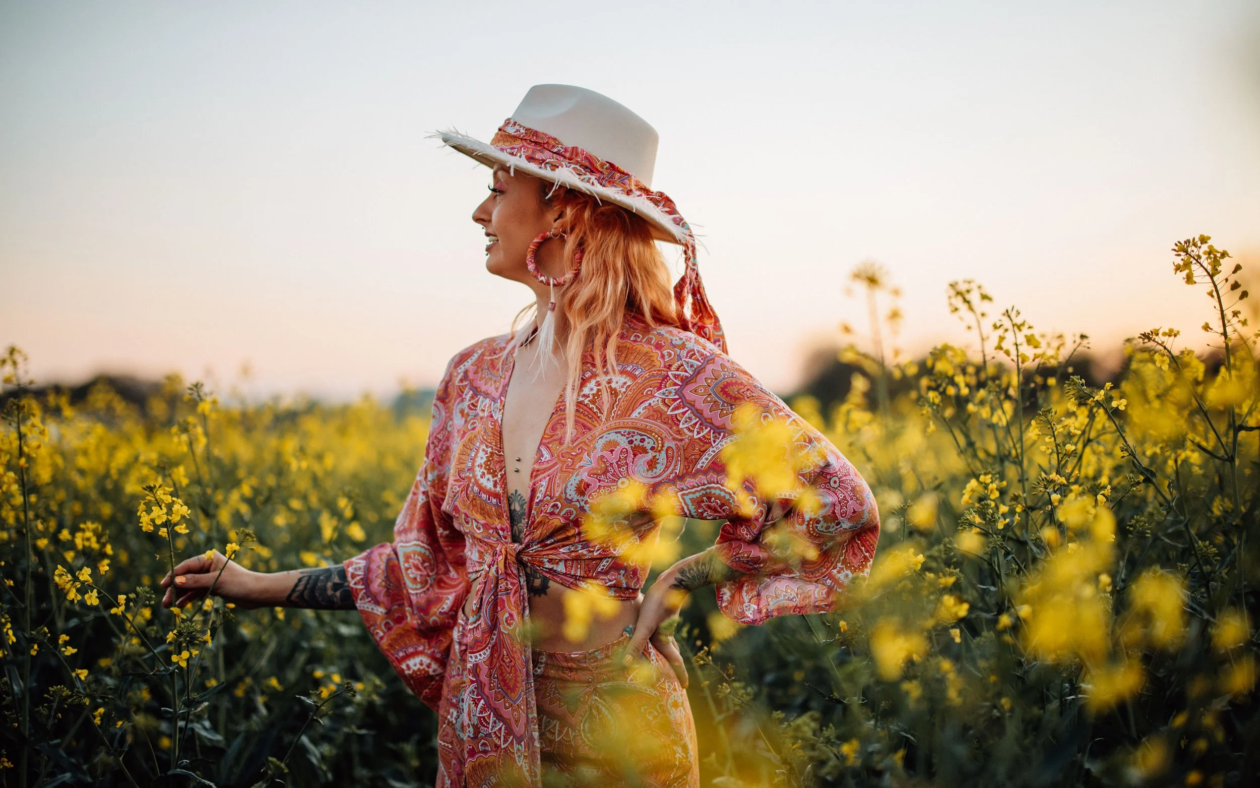 Girl in hippie outfit by the disco spirits looks at Vue in field of yellow flowers