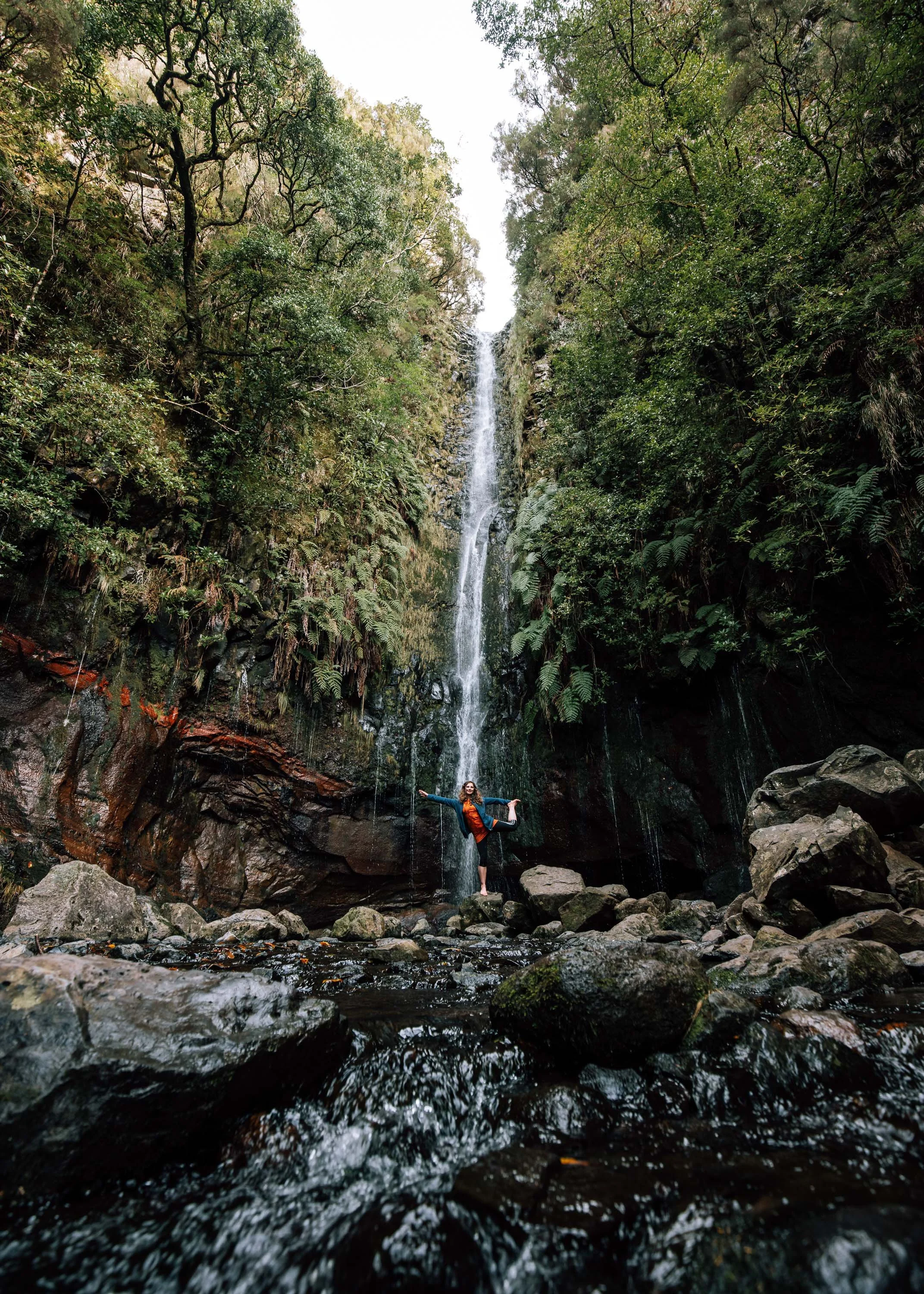  Woman stands in front of waterfall Madeira