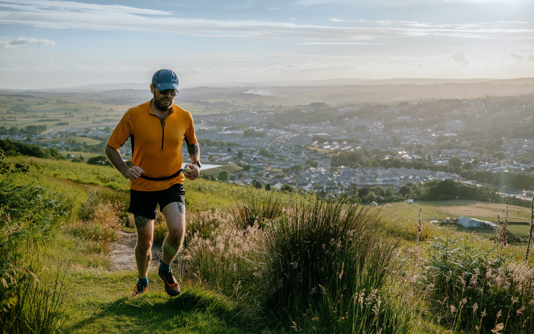 Fell runner runs up hill above Skipton, Yoshire at sunset