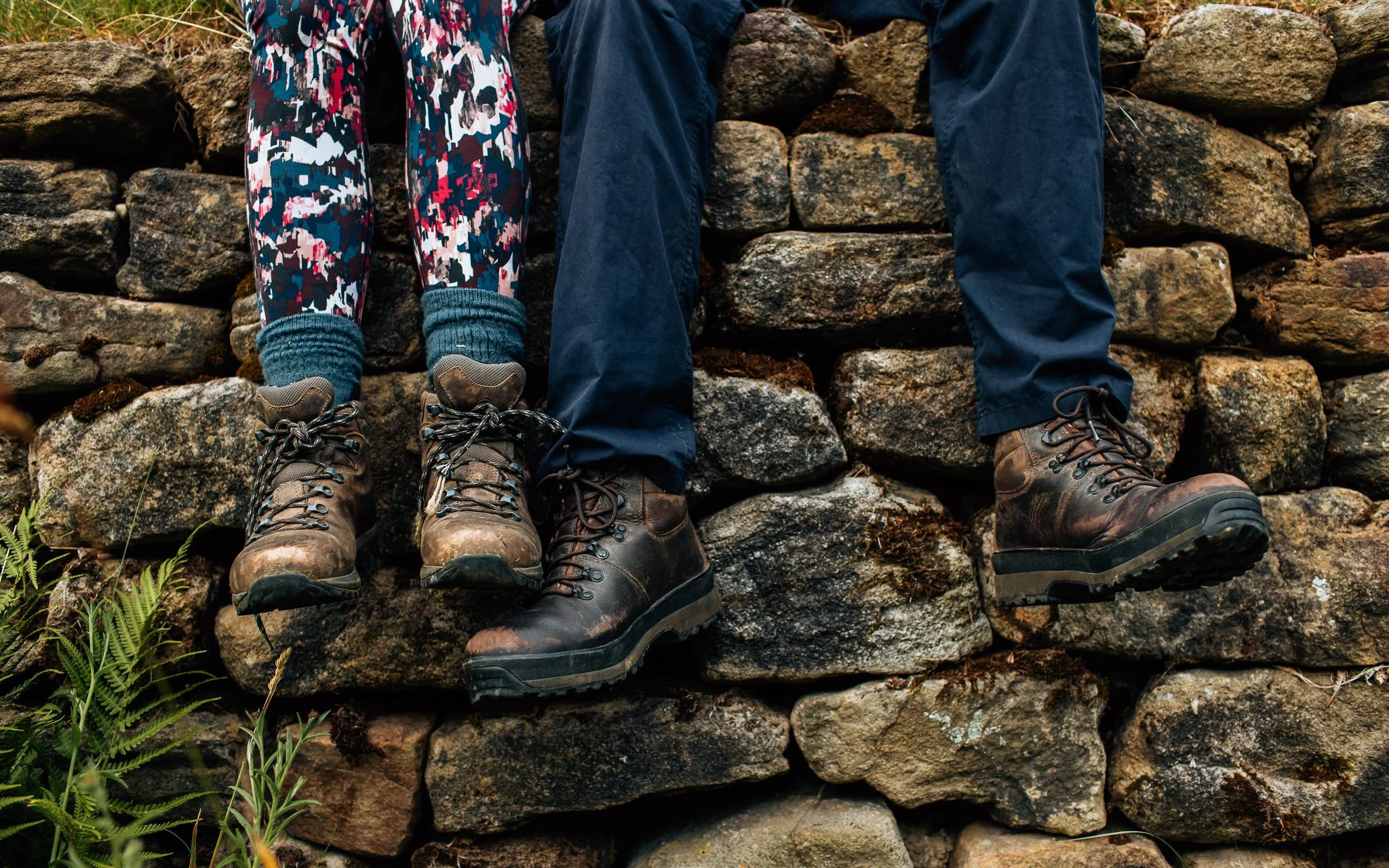 Two walkers sit on a wall feet dangling