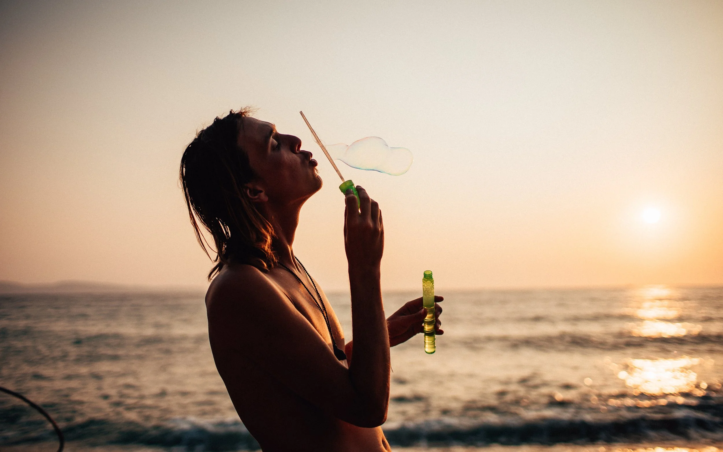  man blows bubbles in the sunset