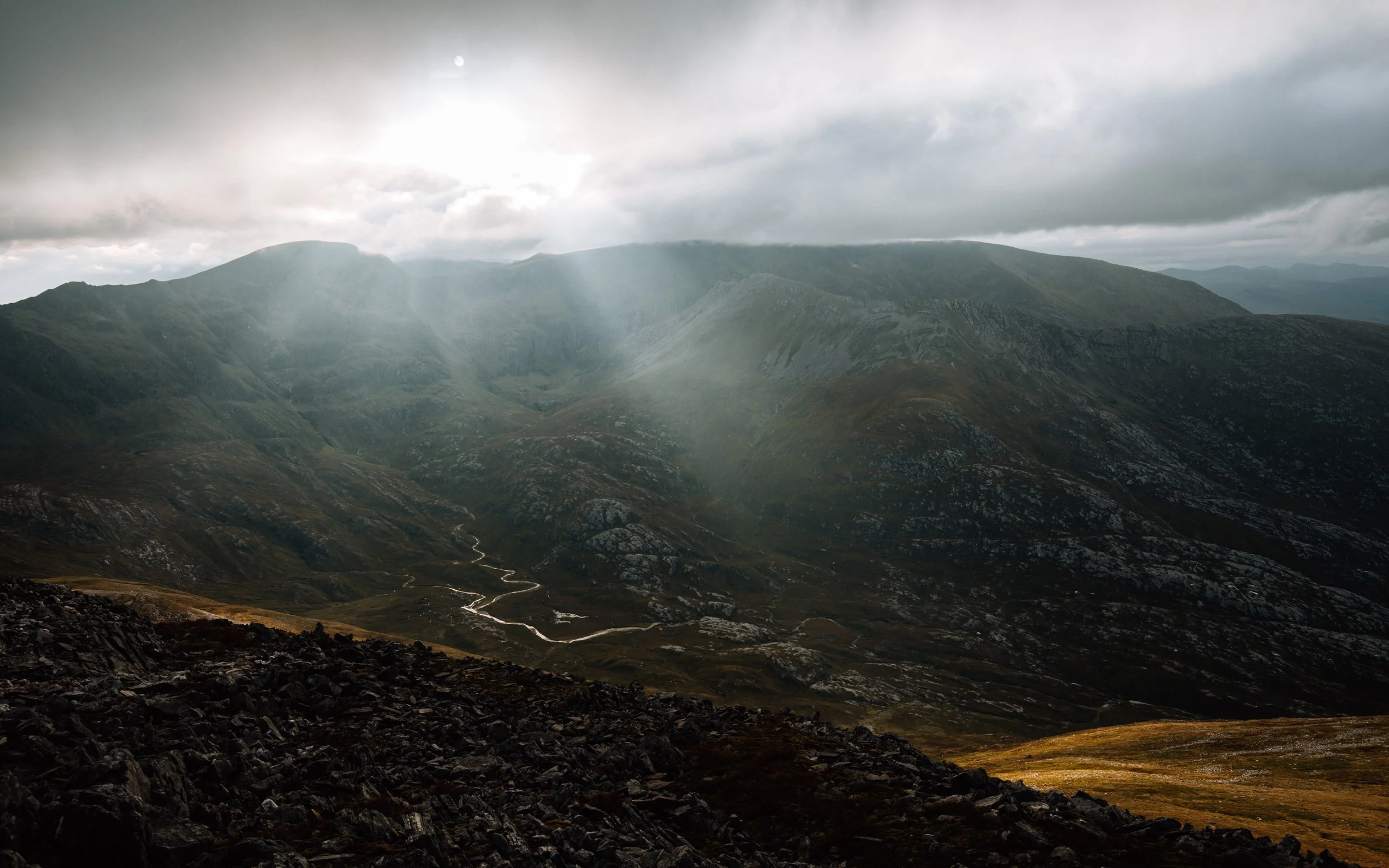  sunlight coming through the clouds above the grey Corries Scotland