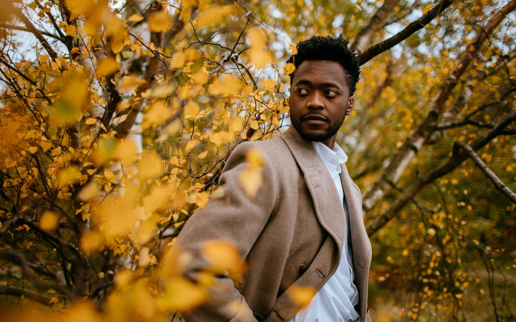 man poses in autumn leaves