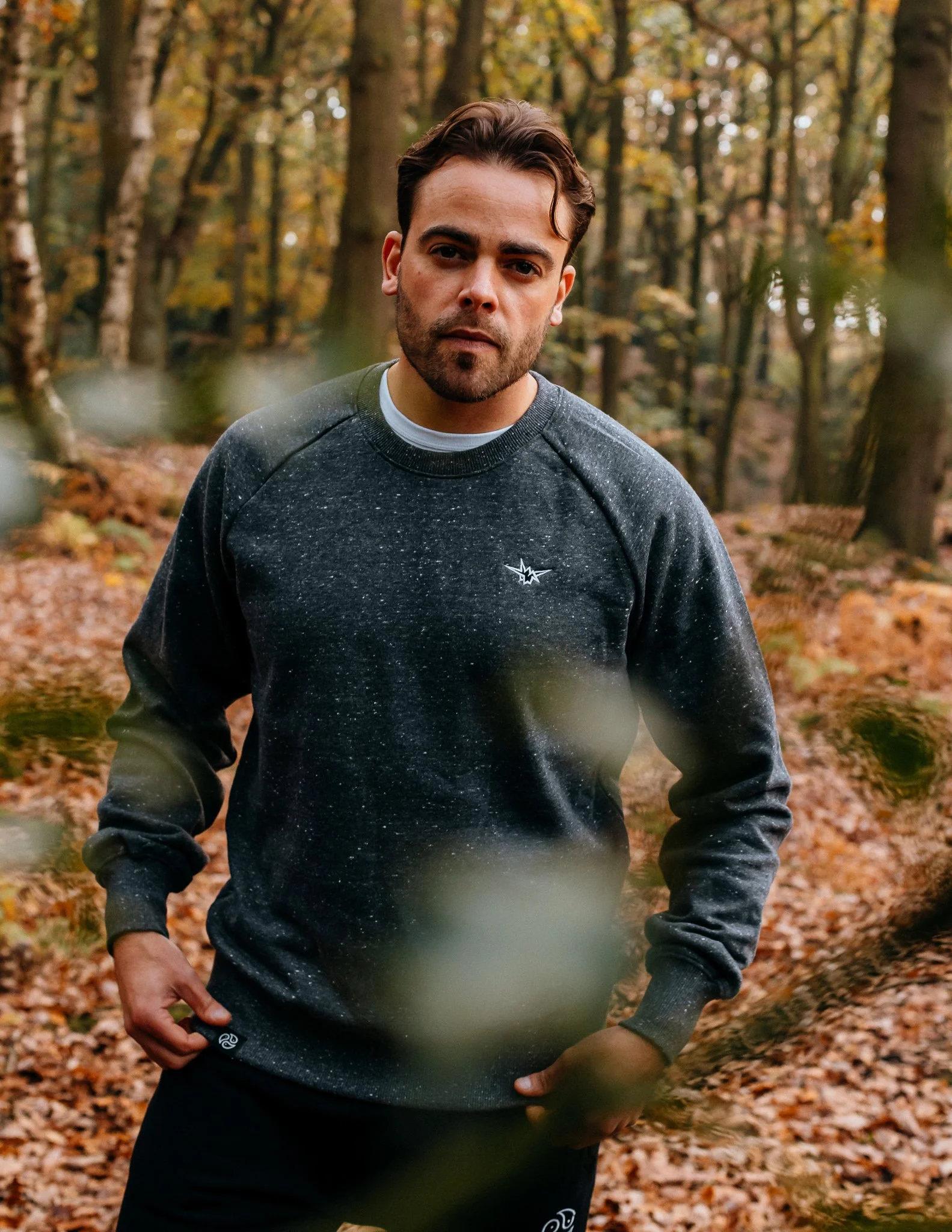Male model stands in Woods in tomoto jumper