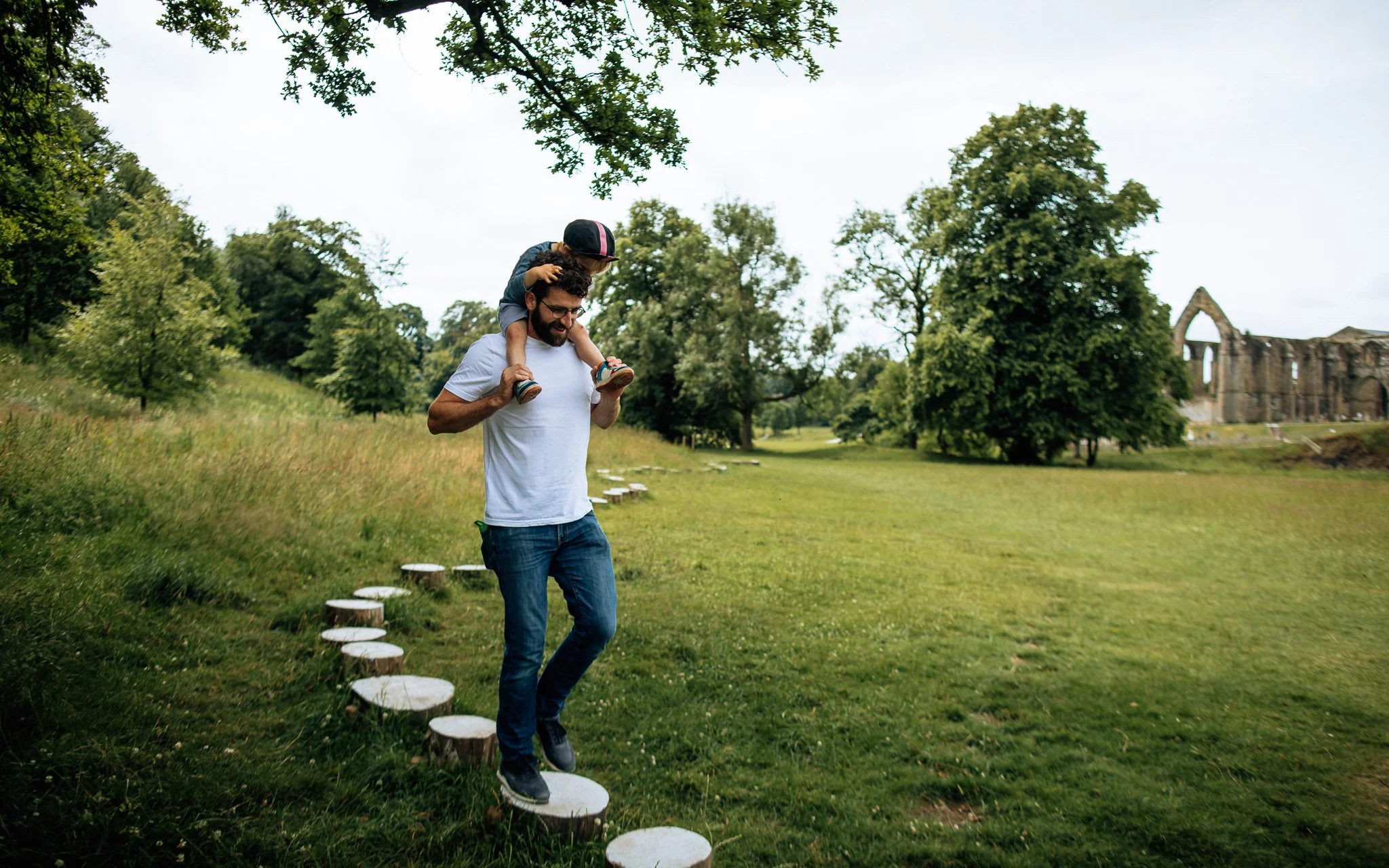 Man walks over, stepping stones with son on shoulders