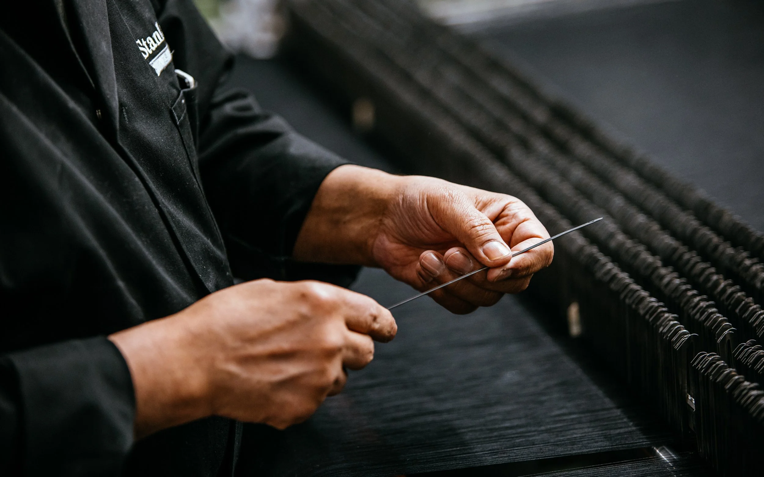 Hands hold Needle by weaving machine