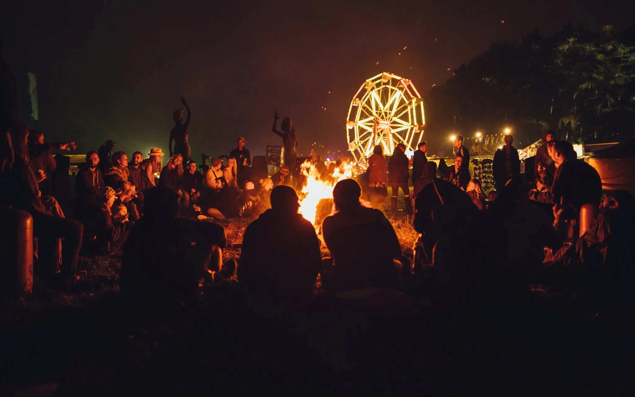  people sit around a campfire at a music festival