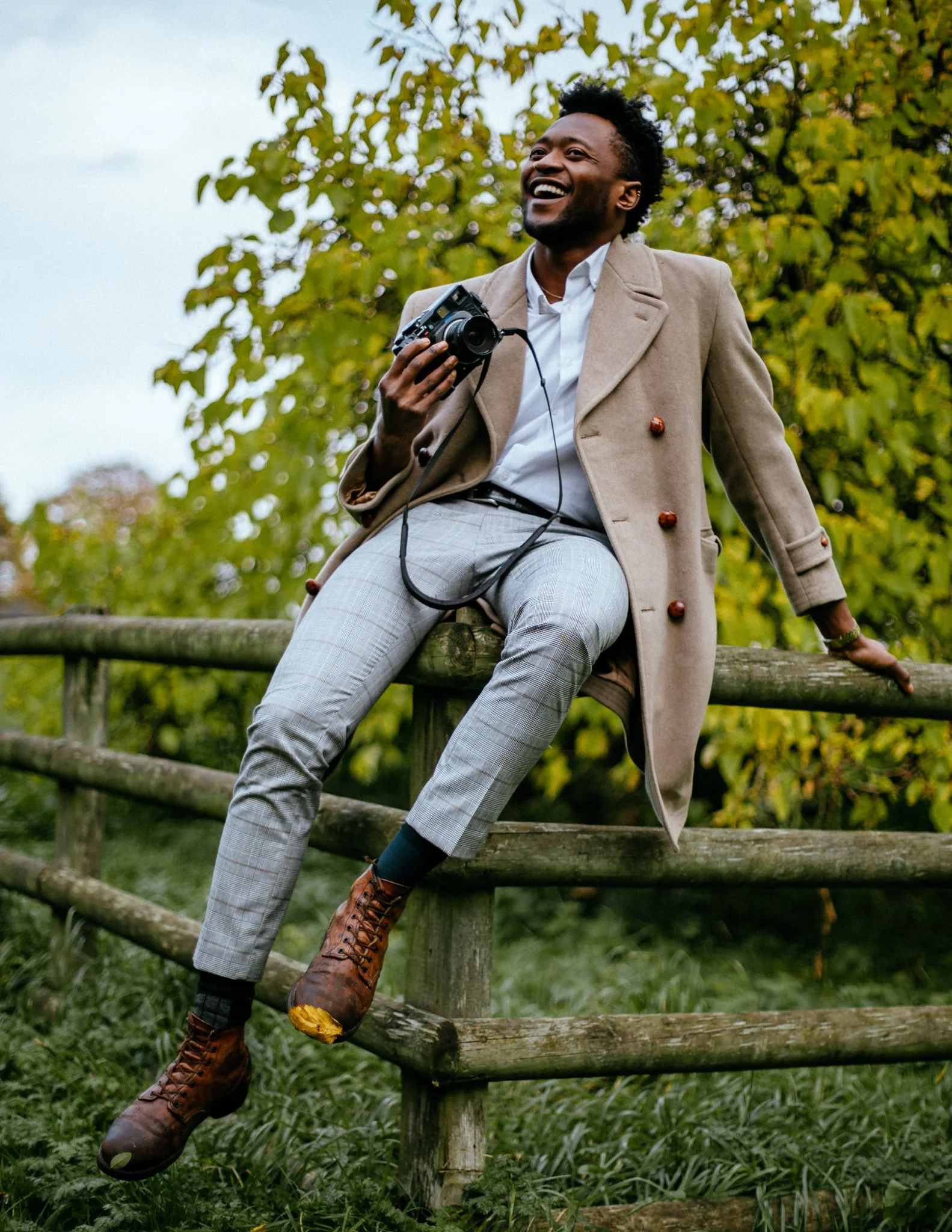 Man sits on a fence with camera