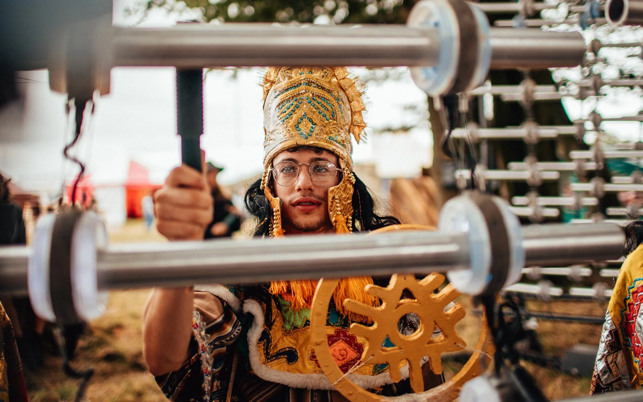  a man dressed in boomtown outfit plays interactive musical instruments at boomtown, fair music festival