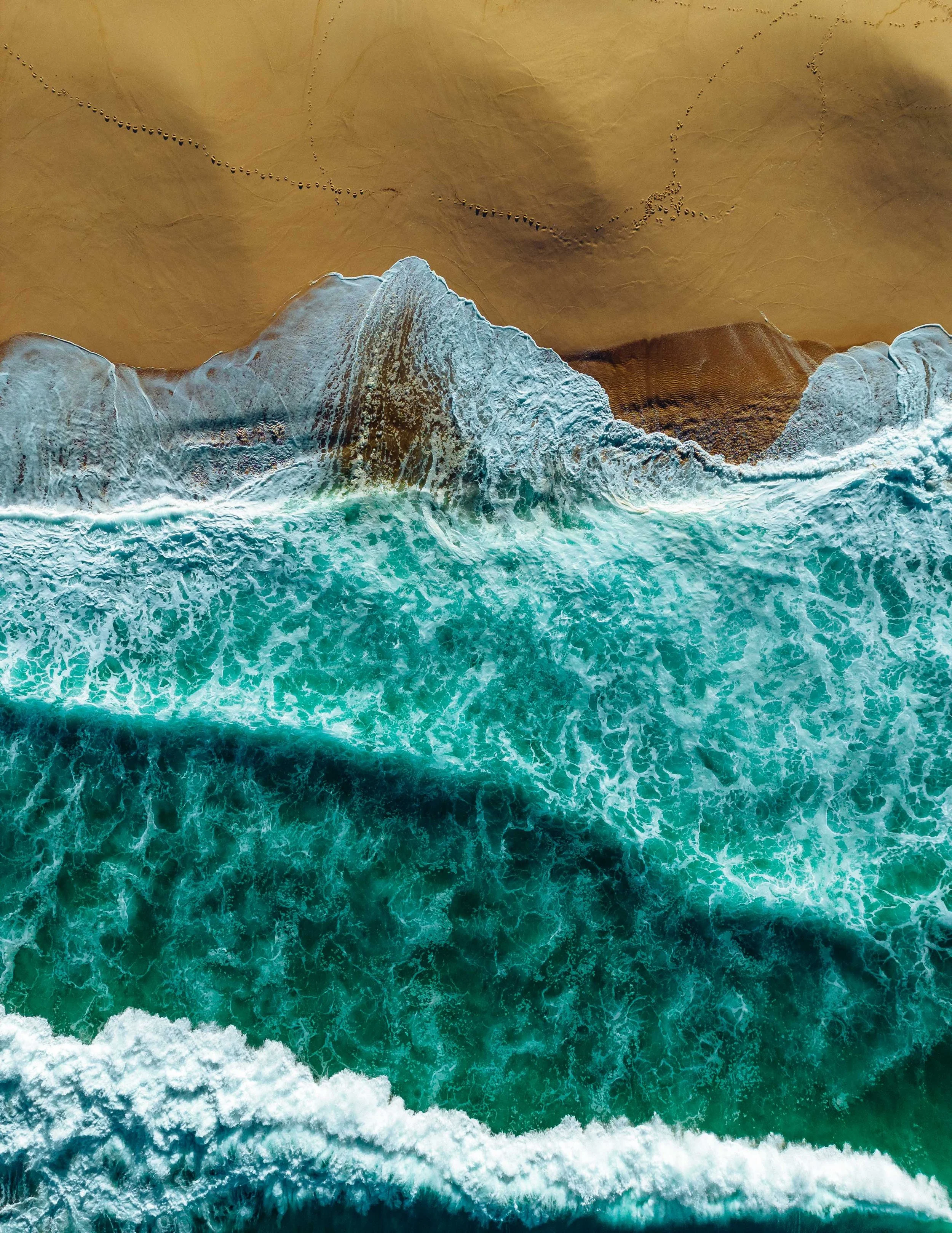  blue waves breaking on the shore of Portugal, yellow sand turquoise sea.