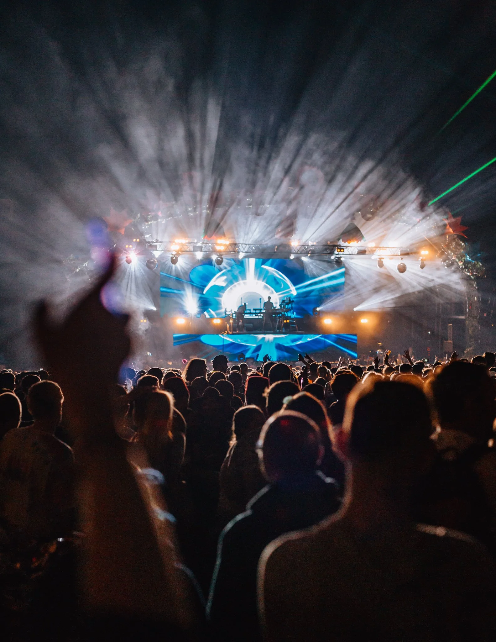 A crowd watch DJs at a music festival