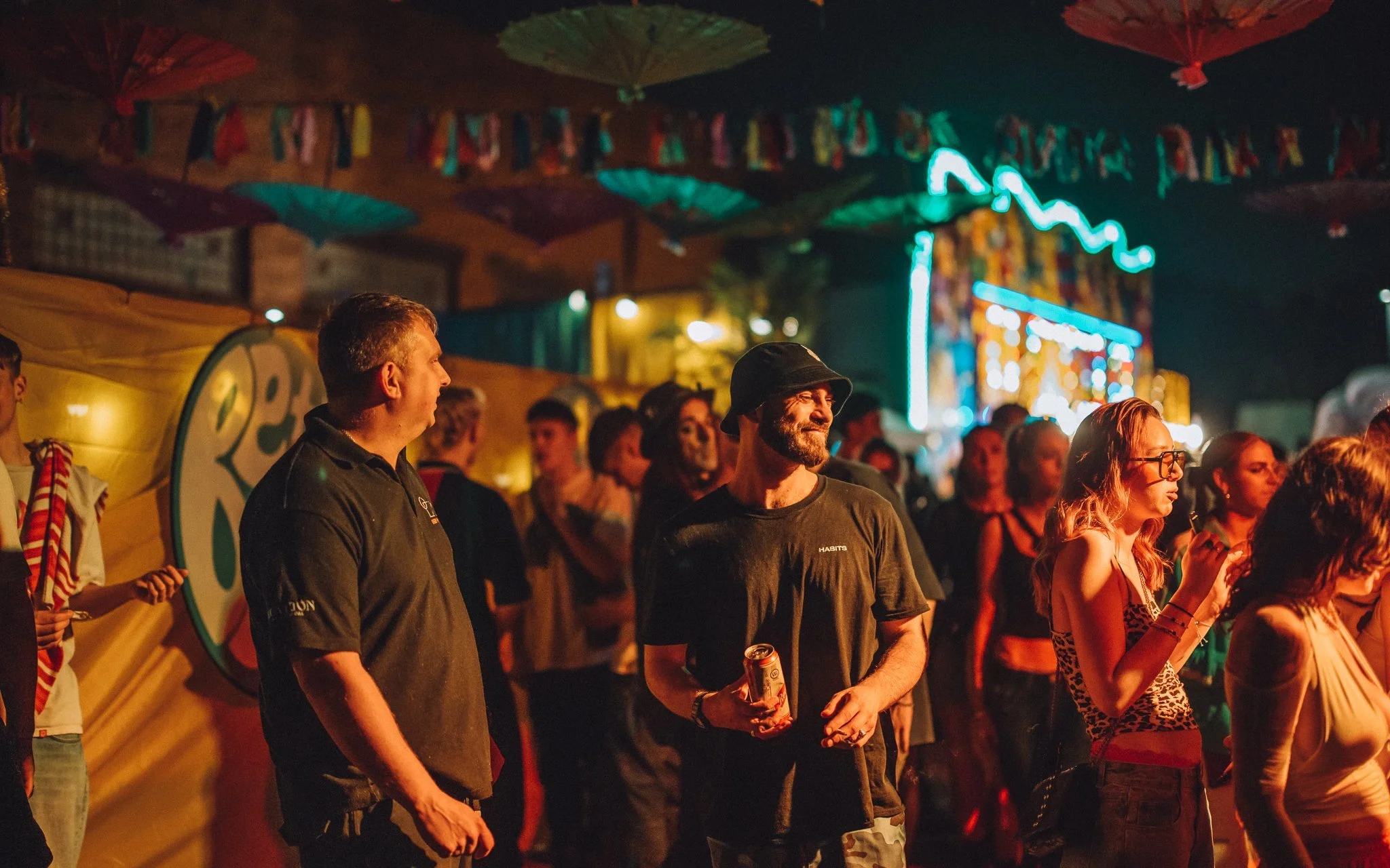 People stand in front of fairground ride at music festival
