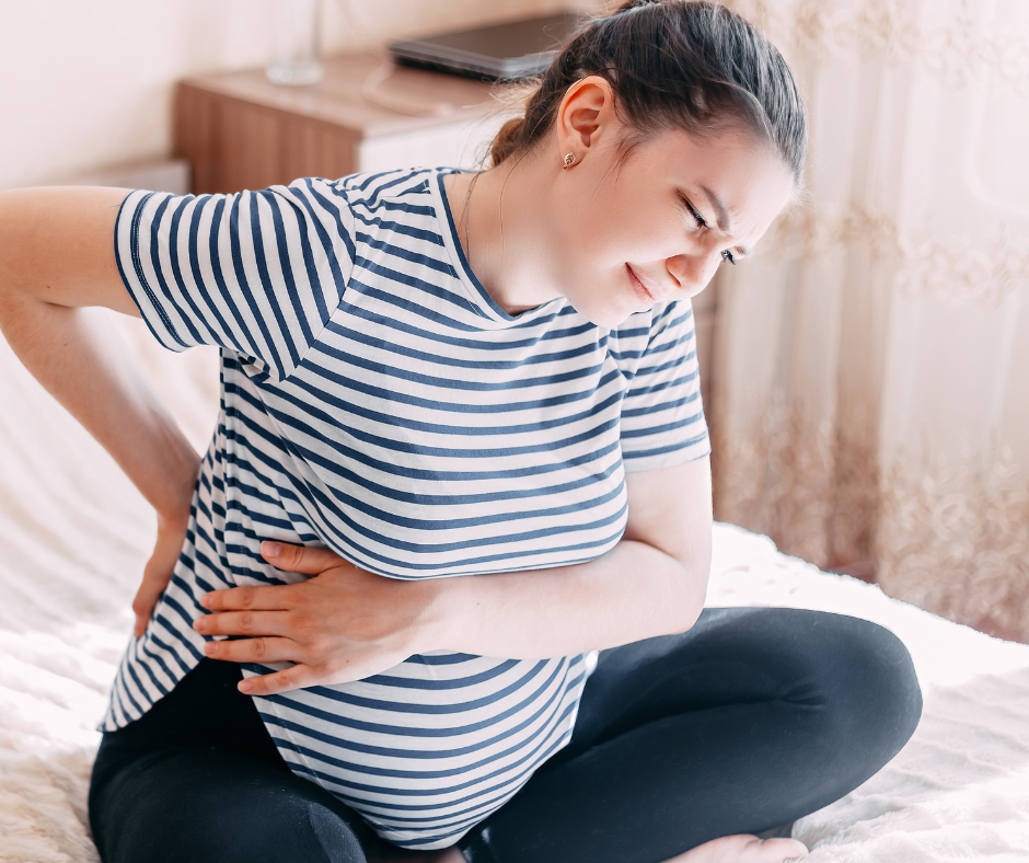 Pregnant lady sitting in bed with back pain (1).png