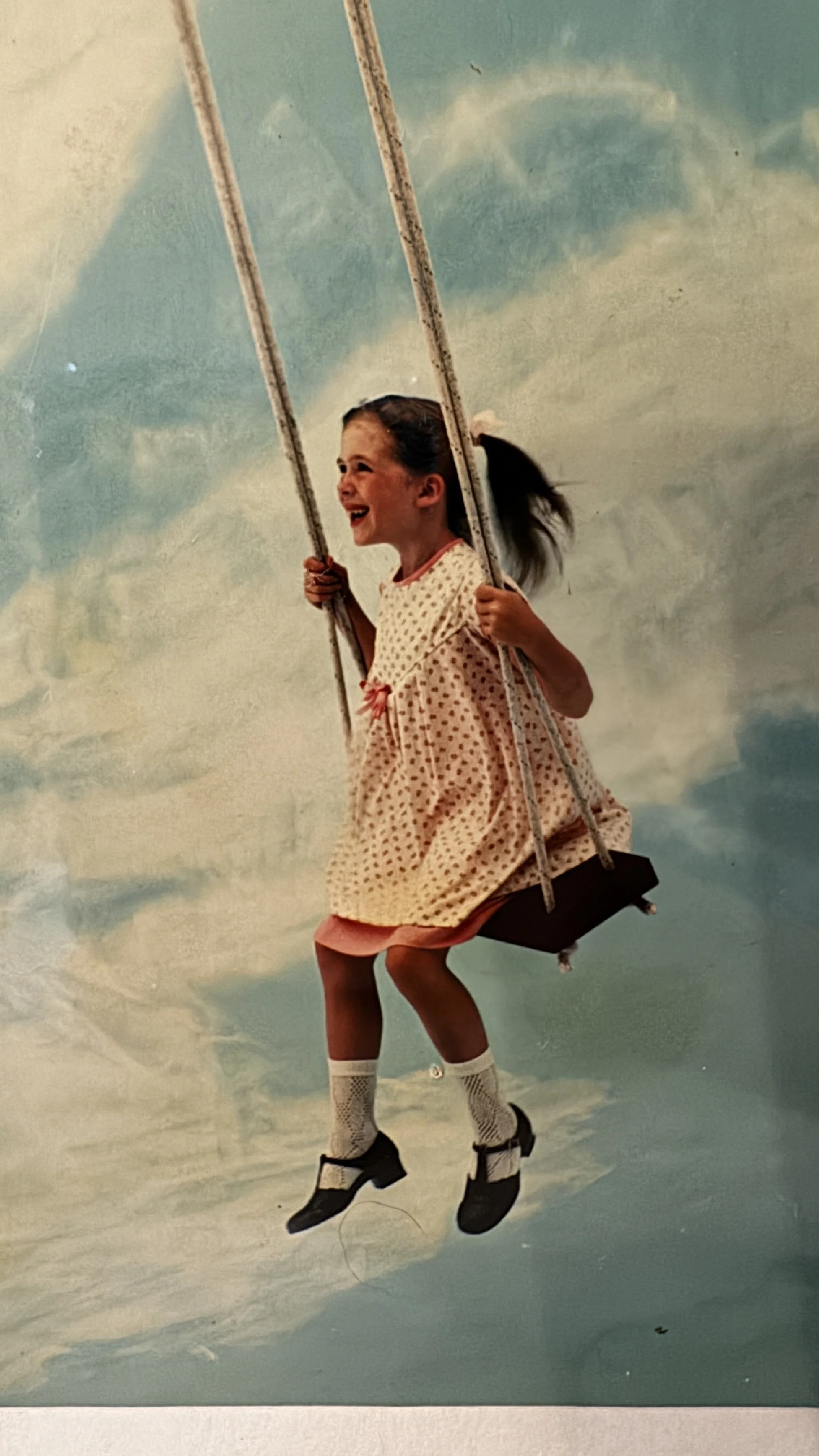 a young girl sits on a swing in a advert from the late 1970's