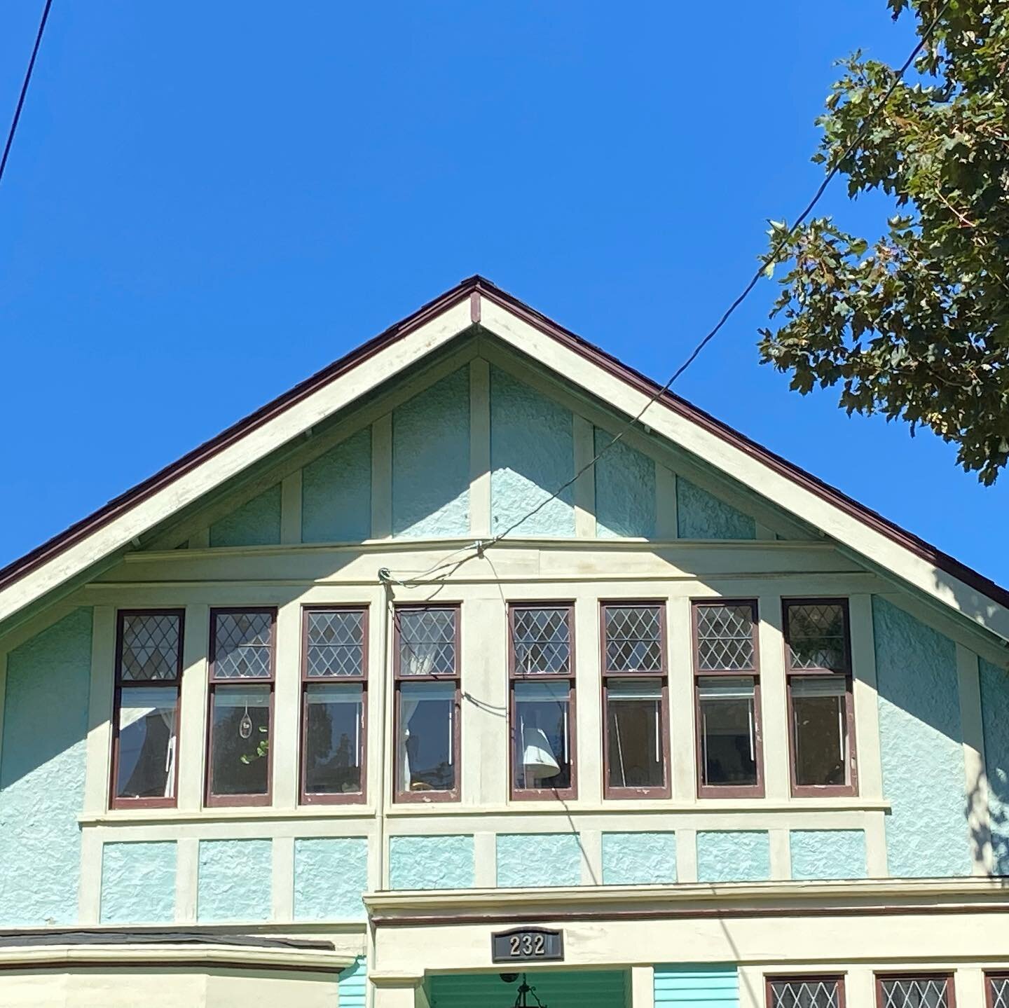 Double-hung diamond-paned leaded lights over single panes on a sweet icy blue 1912 Arts and Crafts house.