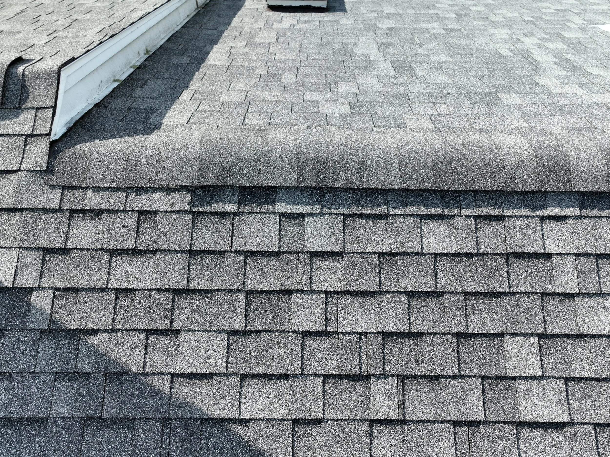 Close-up of a shingled roof with asphalt shingles and a small section of the roof edge.